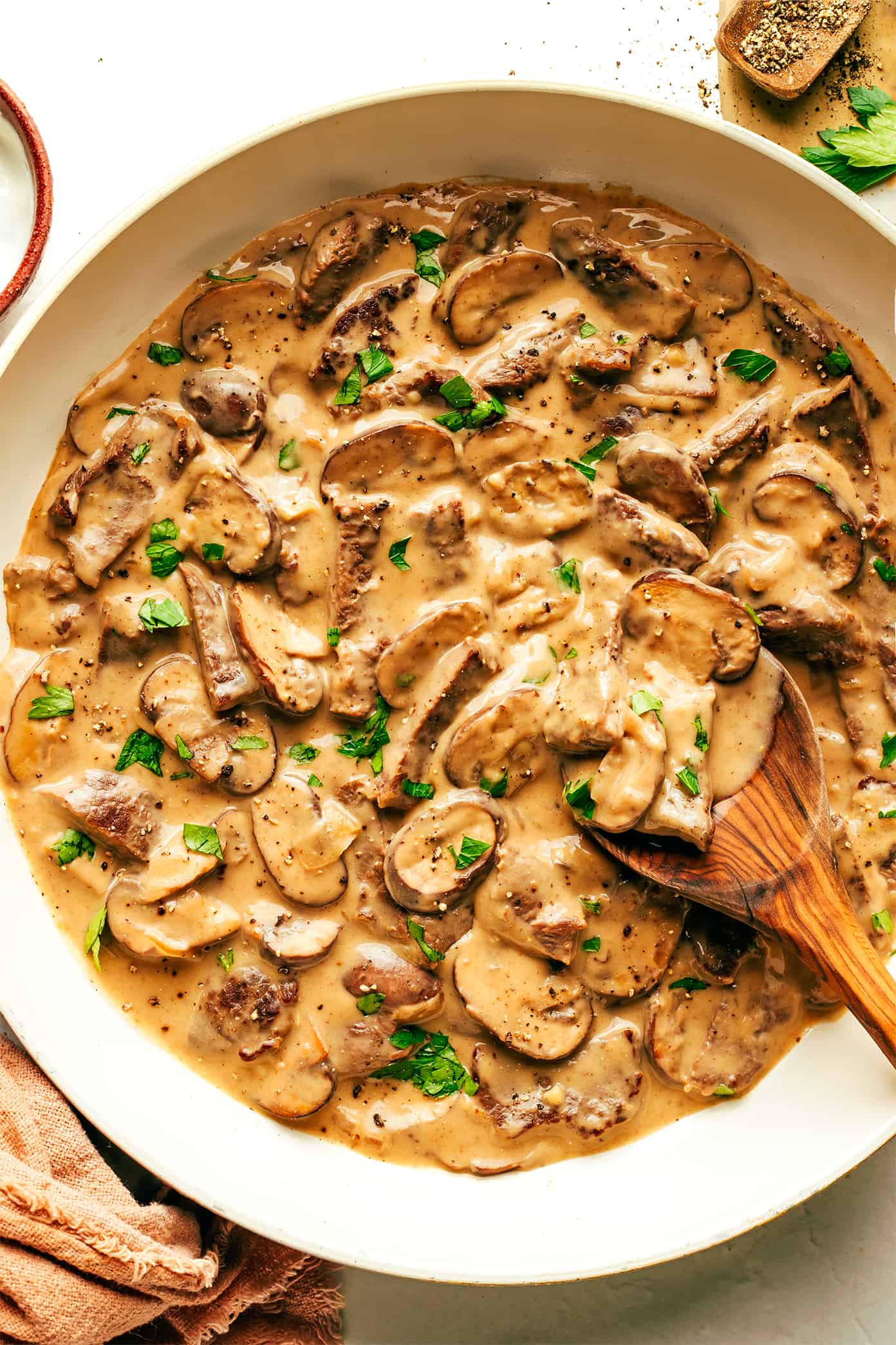 This easy beef stroganoff recipe is made with the most delicious garlicky creamy mushroom sauce and can be ready to go in just 30 minutes. Serve for dinner over noodles, rice, or polenta and enjoy! | gimmesomeoven.com Beef Stroganoff in saute pan with wooden spoon