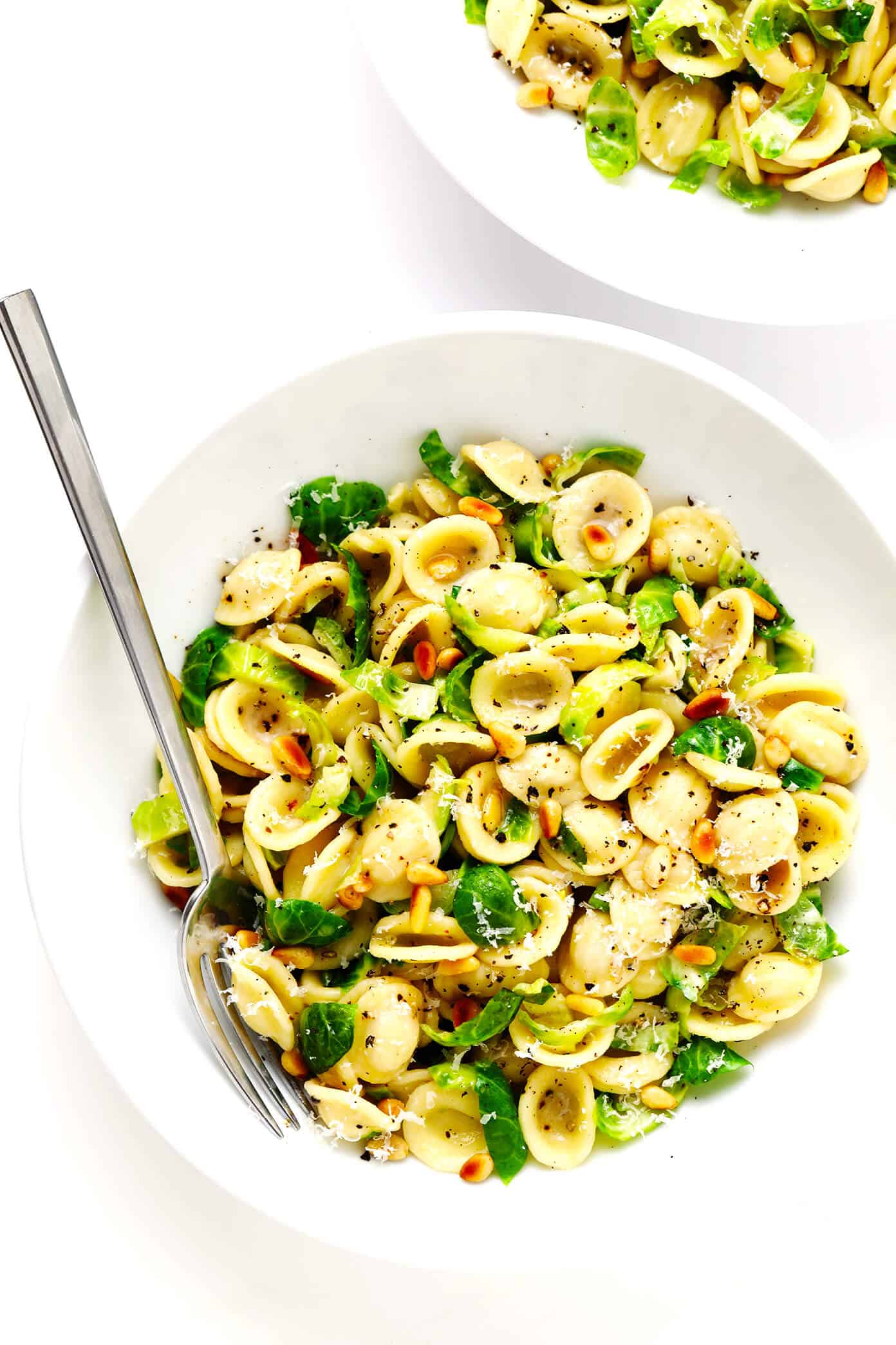 This 30-Minute Brussels Sprouts Parmesan Pasta is made with garlicky shredded Brussels sprouts, toasted pine nuts, and a silky cacio e pepe style cheese and black pepper sauce. It's the perfect easy dinner recipe for fall and winter, and tastes SO delicious. | gimmesomeoven.com #pasta #brussels #vegetarian #italian #cacioepepe #parmesan #sauce #dinner Brussels Sprouts Pasta in Serving Bowls