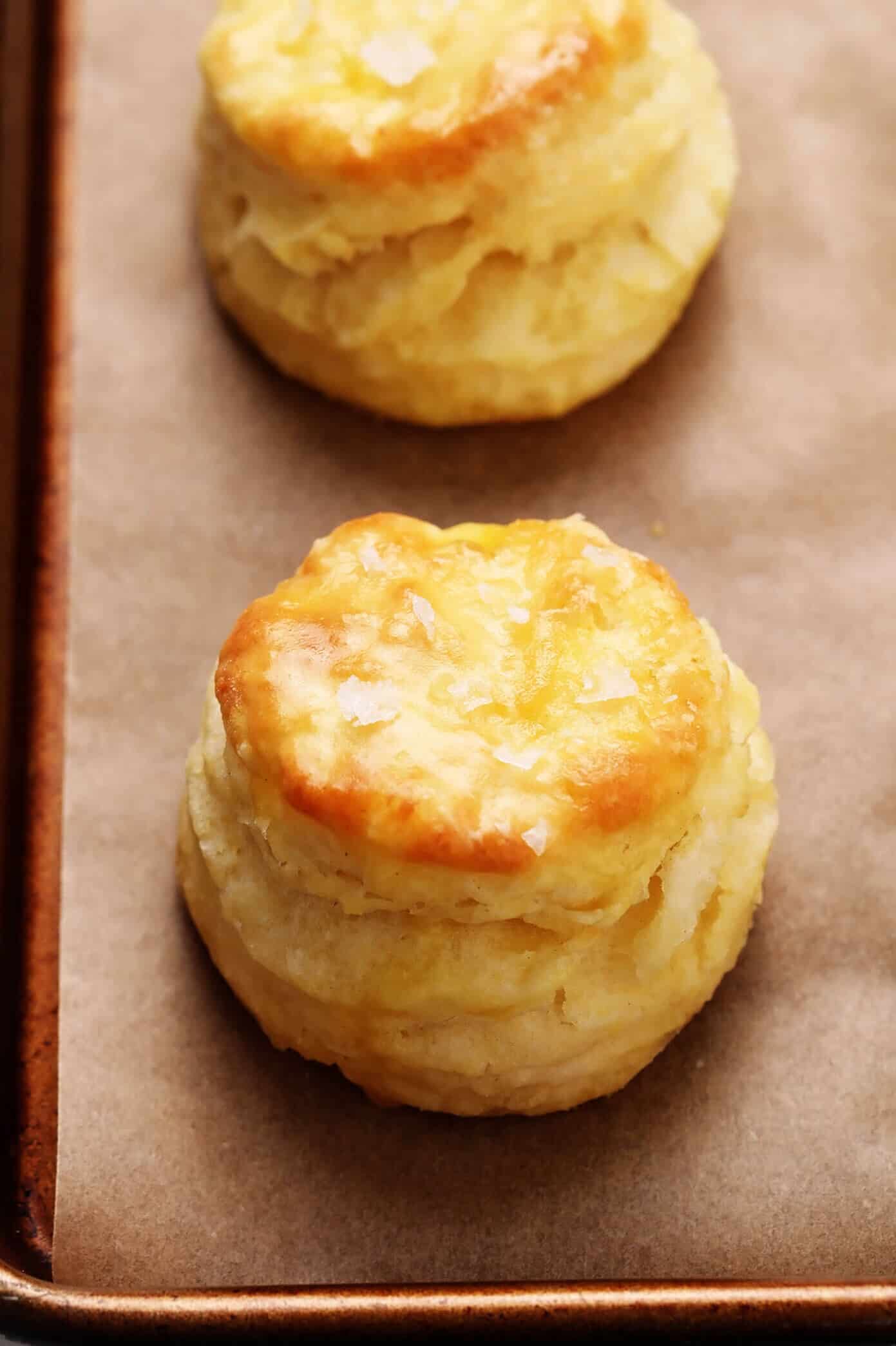 My favorite homemade buttermilk biscuit recipe -- easy to make, perfectly soft and tall and flaky, and always SO buttery and delicious. Serve them for breakfast with jam or gravy, as a side dish for lunch or dinner, or as a topping for chicken pot pie or your favorite casserole! | gimmesomeoven.com #biscuit #roll #bread #recipe #buttermilk #breakfast #brunch #side #vegetarian #baking Buttermilk Biscuits sprinkled with flaky sea salt closeup