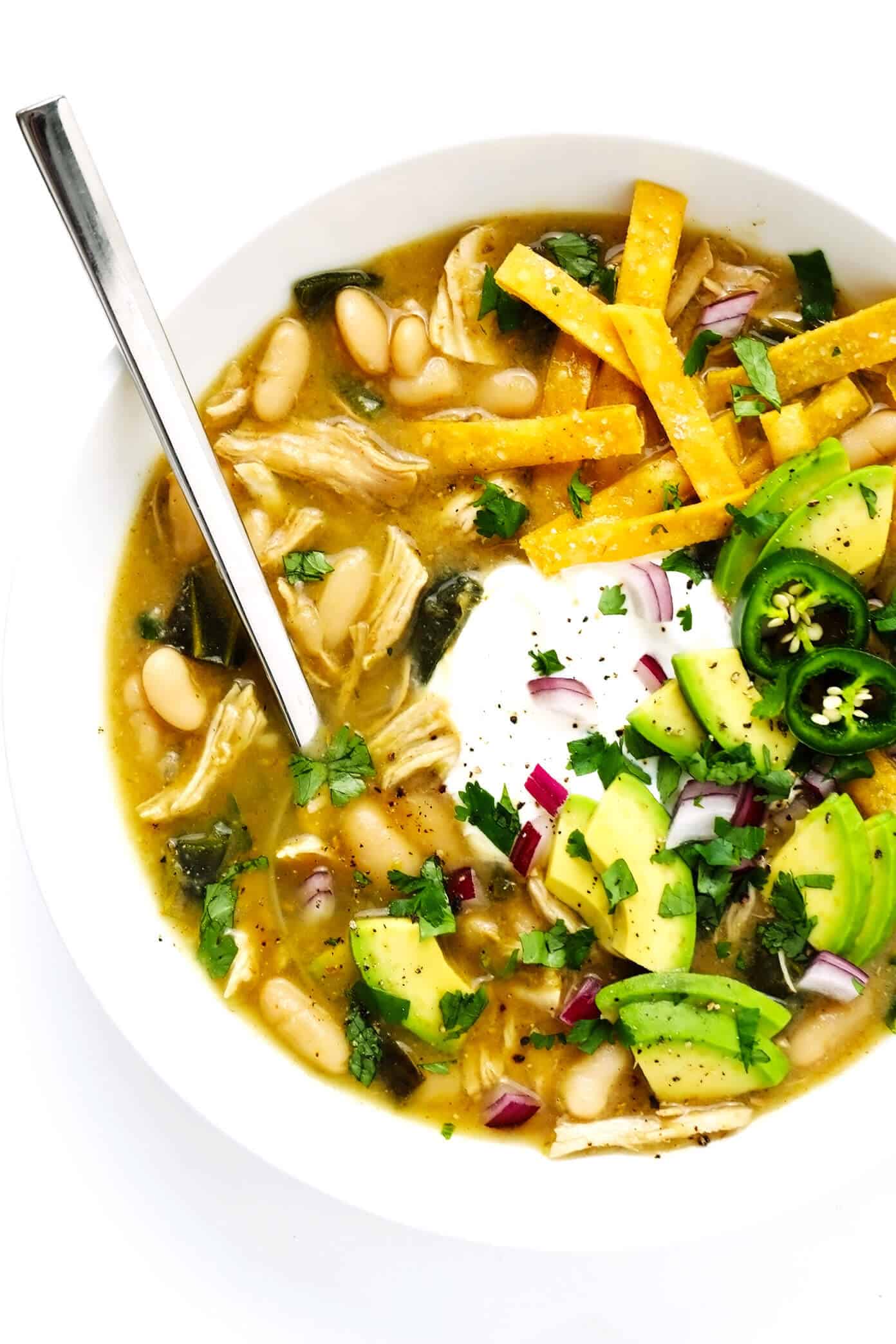 This Poblano White Chicken Chili recipe comes together quickly in less than 30 minutes and is SO flavorful and comforting. Perfect for easy soup dinners and healthy meal prep! | gimmesomeoven.com #chicken #chili #soup #mexican #healthy #glutenfree #mealprep #freezermeal #beans Poblano White Chicken Chili in Bowl with Avocado and Cilantro Toppings