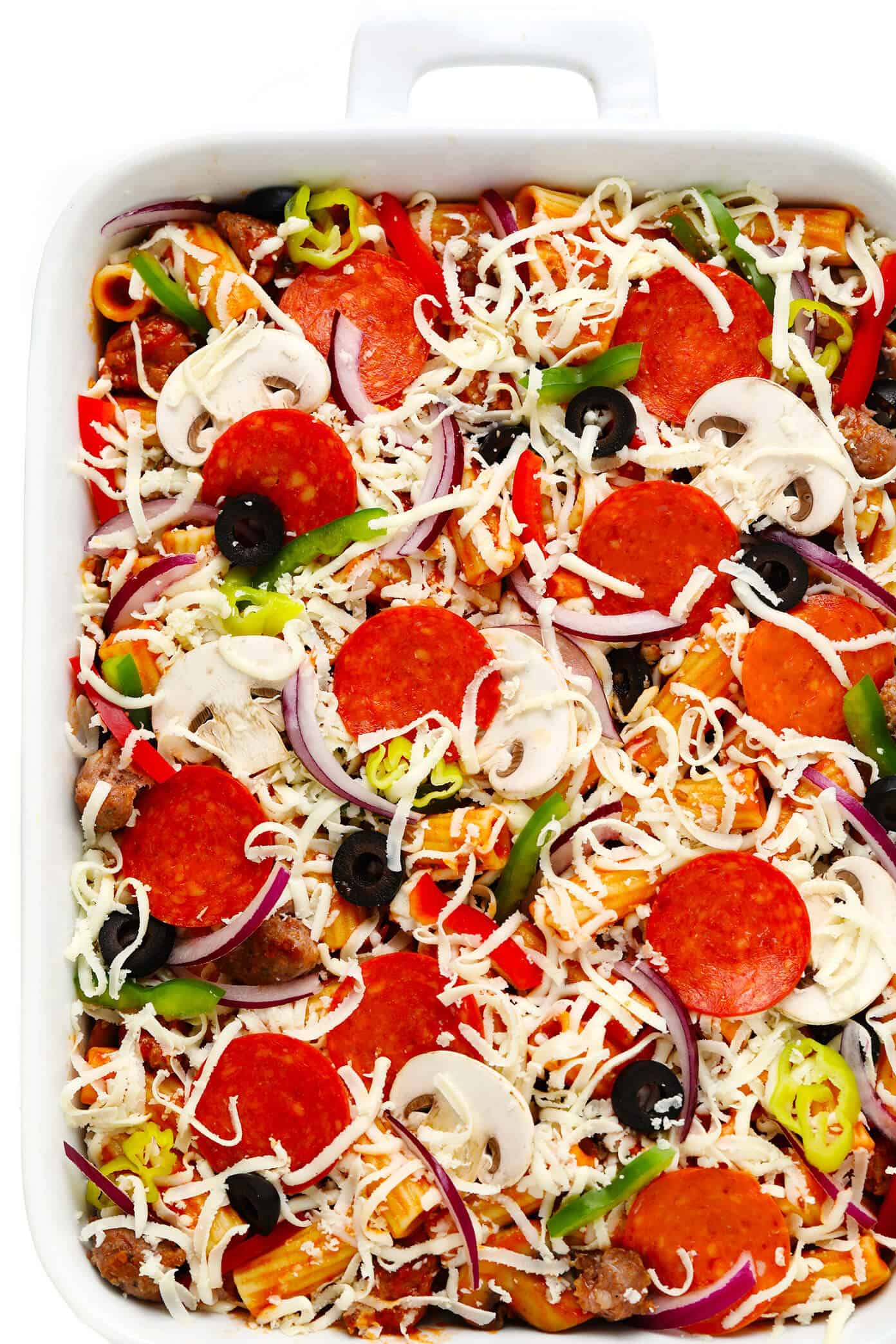 This "Pizza" Baked Ziti recipe is totally fun to make with all of your favorite pizza toppings! Simply bake them up with your favorite pasta, marinara sauce and cheeses, then serve up this casserole while it's hot and bubbly for a delicious Italian dinner! Feel free to use gluten-free, vegetarian and/or vegan ingredients if you prefer. | gimmesomeoven.com #pizza #pasta #bakedziti #casserole #bake #italian #dinner #easy #vegetarian #glutenfree Pizza Baked Ziti Ingredients In Pan Before Baking
