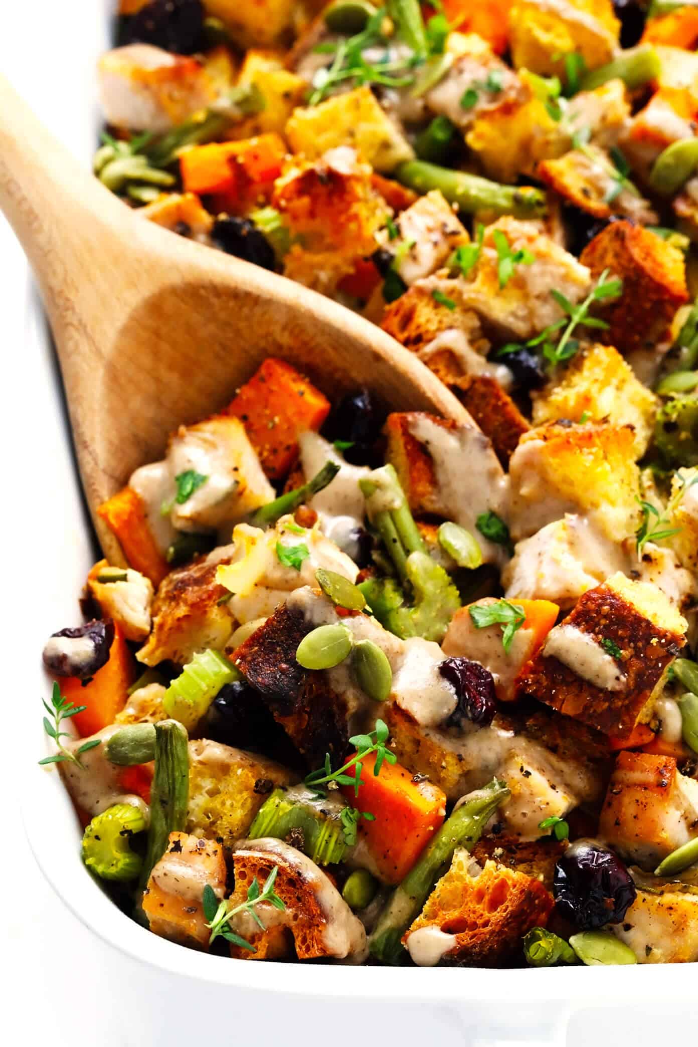 This All-In-One Thanksgiving Casserole recipe is made with everyone's holiday faves -- turkey, herbed stuffing, green beans, sweet potatoes, cranberries, all drizzled with a quick homemade mushroom gravy. It's the perfect easy bake when you don't feel like cooking a dozen different side dishes and SO delicious! | gimmesomeoven.com #thanksgiving #casserole #turkey #stuffing #cranberry #sweetpotato #dinner #easy Thanksgiving Casserole Recipe Closeup with Serving Spoon