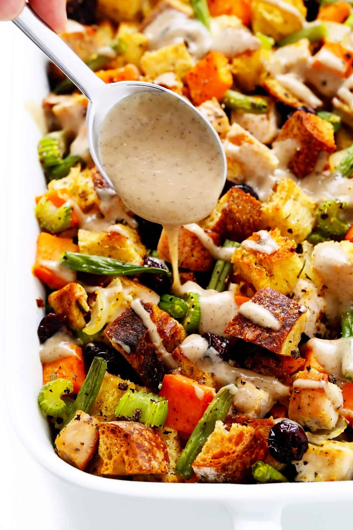This All-In-One Thanksgiving Casserole recipe is made with everyone's holiday faves -- turkey, herbed stuffing, green beans, sweet potatoes, cranberries, all drizzled with a quick homemade mushroom gravy. It's the perfect easy bake when you don't feel like cooking a dozen different side dishes and SO delicious! | gimmesomeoven.com #thanksgiving #casserole #turkey #stuffing #cranberry #sweetpotato #dinner #easy Drizzling Gravy on Thanksgiving Casserole
