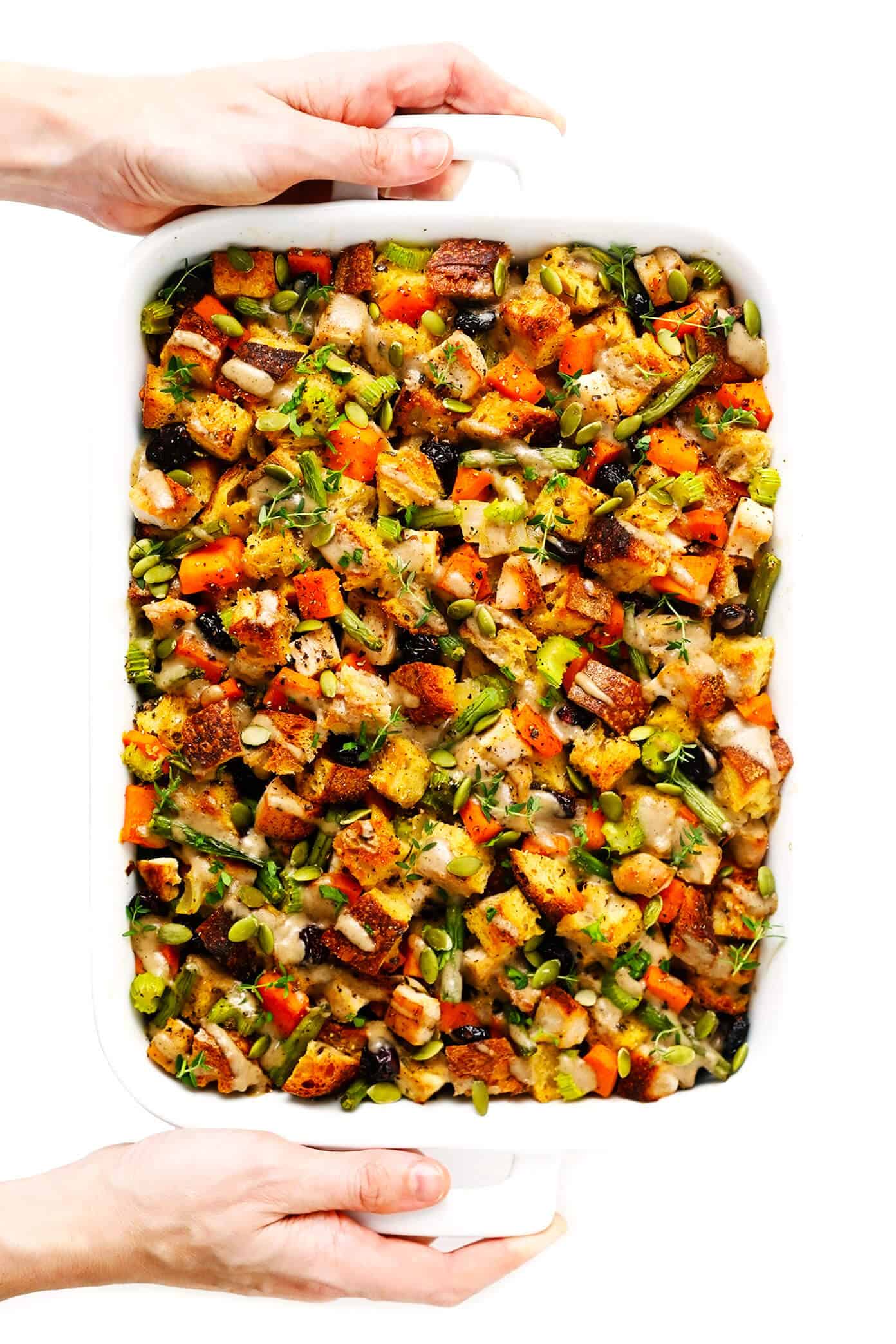 This All-In-One Thanksgiving Casserole recipe is made with everyone's holiday faves -- turkey, herbed stuffing, green beans, sweet potatoes, cranberries, all drizzled with a quick homemade mushroom gravy. It's the perfect easy bake when you don't feel like cooking a dozen different side dishes and SO delicious! | gimmesomeoven.com #thanksgiving #casserole #turkey #stuffing #cranberry #sweetpotato #dinner #easy Holding Thanksgiving Casserole with Turkey and Sweet Potatoes