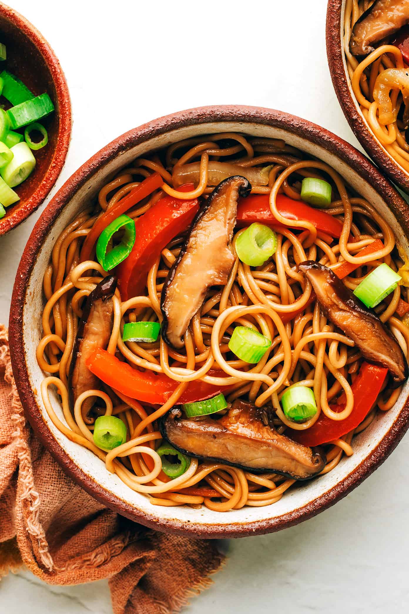This Chinese-inspired chow mein recipe is easy to whip up in just 25 minutes and tossed with a delicious stir-fry sauce. Feel free to add beef, chicken, pork, shrimp, tofu, or any other extra veggies you might like too! | gimmesomeoven.com Bowl of chow mein with mushrooms, red peppers and green onions