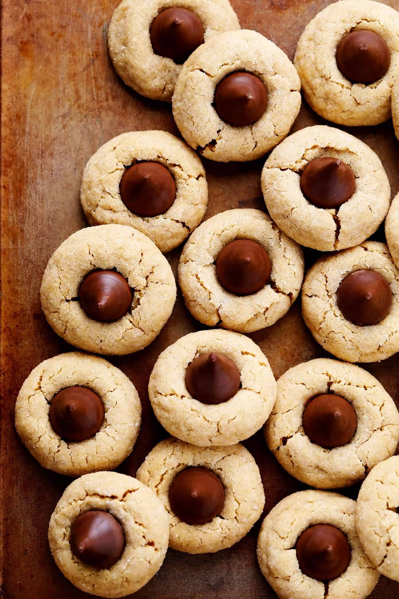 This peanut butter blossoms recipe is made with extra peanut butter, topped with Hershey's Kisses (or peanut butter cups), and perfectly soft and chewy and crackled. Perfect for Christmas or holiday baking, or anytime you have a cookie craving! | gimmesomeoven.com Peanut Butter Kiss Cookies on Baking Sheet