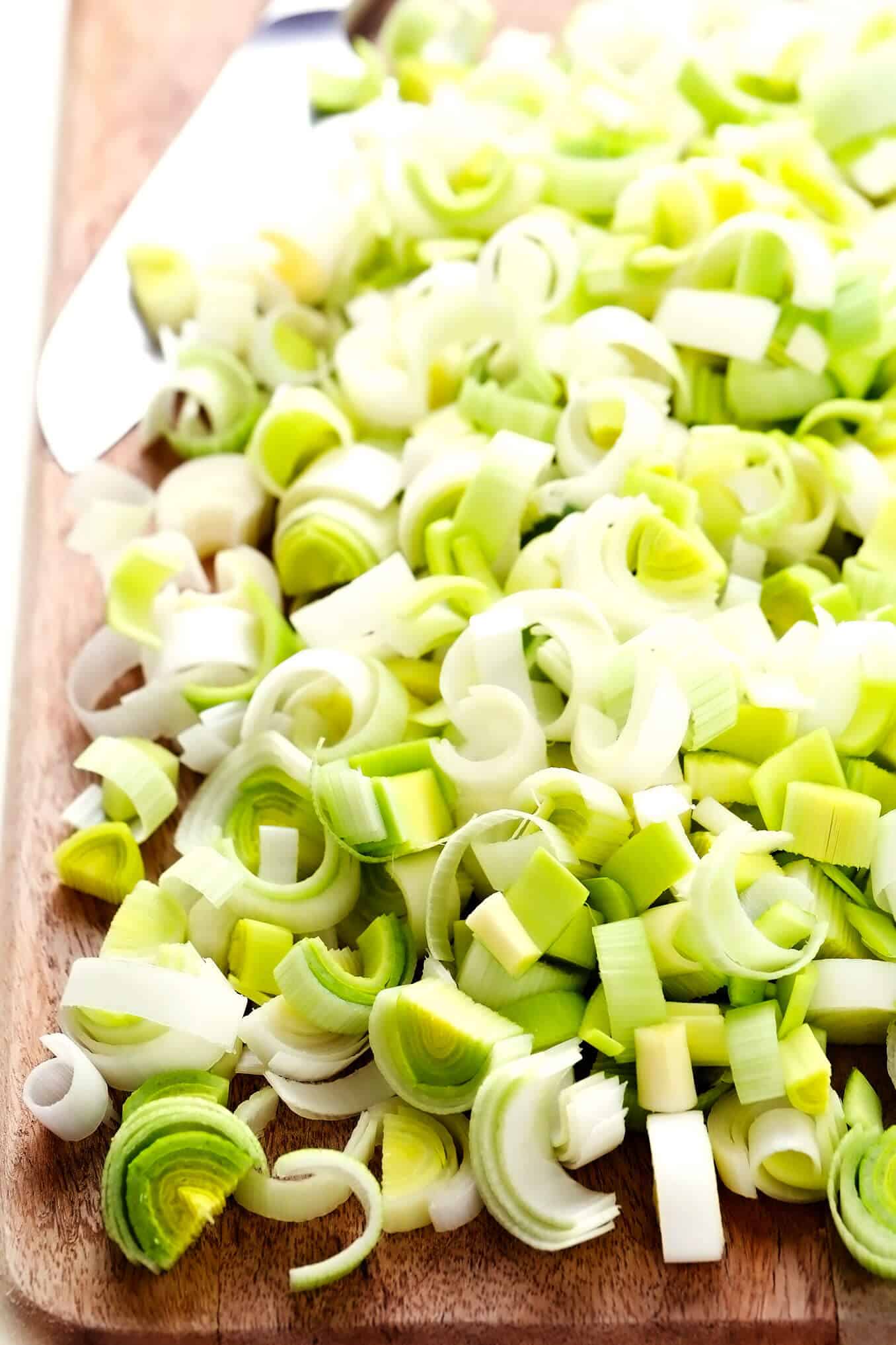 This Rustic Potato Leek Soup is easy to make in about 35 minutes, it's naturally gluten-free, vegetarian, vegan, and it's made with the most delicious, light, garlic-herb broth. A quick, easy and healthy dinner recipe that's always so comforting! (Feel free to add croutons or a sprinkle of Parmesan cheese too!) | gimmesomeoven.com #soup #potato #leek #french #onion #healthy #glutenfree #vegetarian #vegan #dinner #mealprep Chopped Leeks On Cutting Board