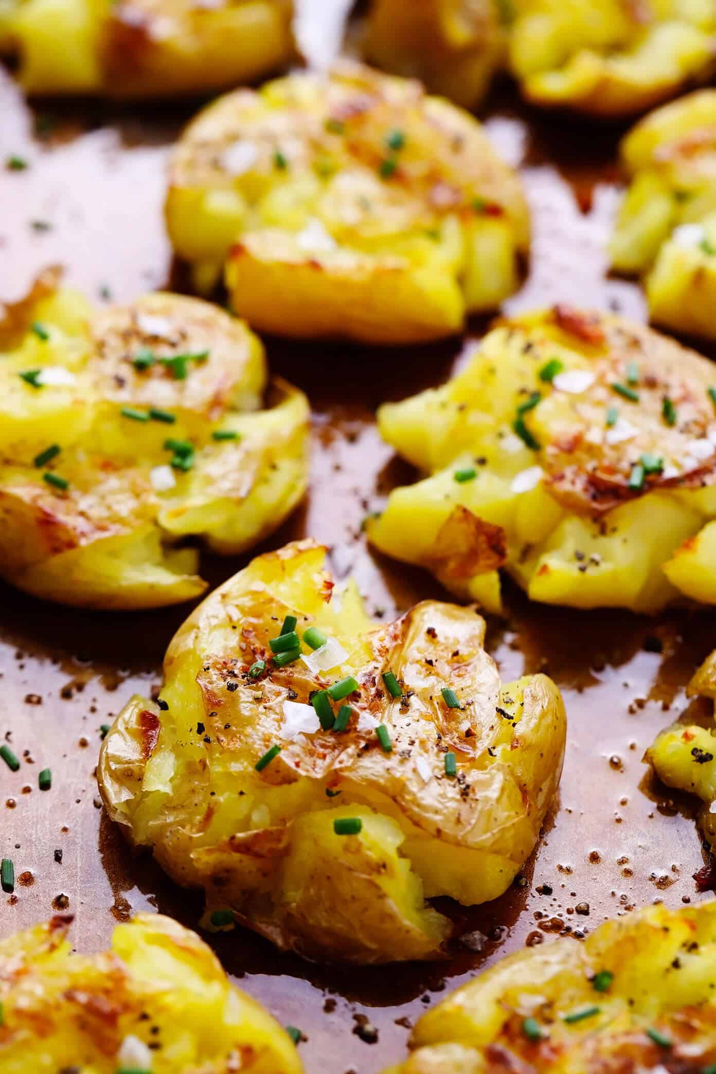 This Smashed Potatoes recipe is easy to make, irresistibly soft and crispy, and full of the best garlicky, buttery flavors. Feel free to add cheese, fresh herbs, or a pinch of flaky sea salt to this simple side dish if you'd like too! | gimmesomeoven.com #smashed #potatoes #roasted #garlic #butter #side #christmas #holiday #dinner Garlic Smashed Potatoes Closeup on Baking Sheet