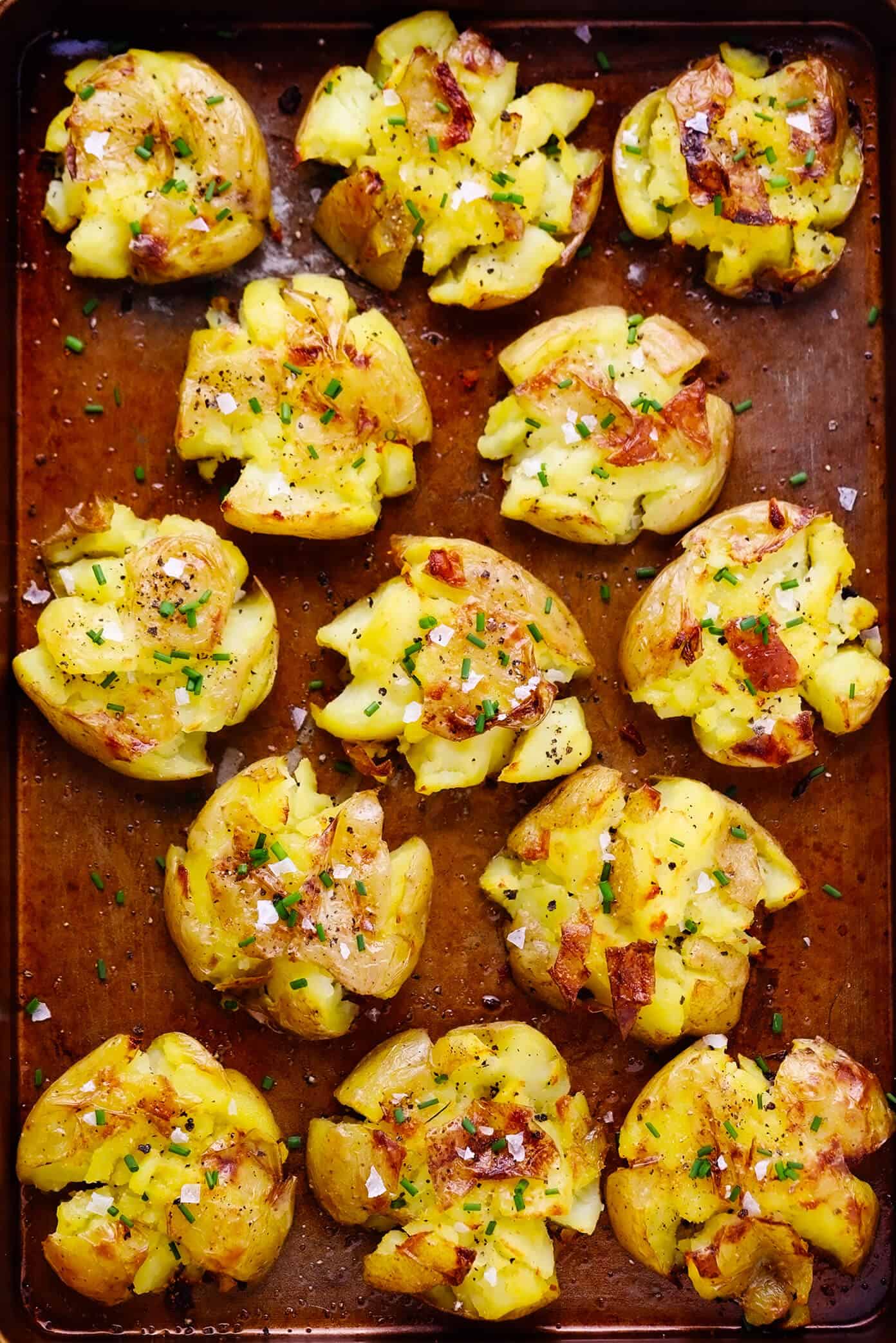 This Smashed Potatoes recipe is easy to make, irresistibly soft and crispy, and full of the best garlicky, buttery flavors. Feel free to add cheese, fresh herbs, or a pinch of flaky sea salt to this simple side dish if you'd like too! | gimmesomeoven.com #smashed #potatoes #roasted #garlic #butter #side #christmas #holiday #dinner Garlic smashed potatoes on baking sheet
