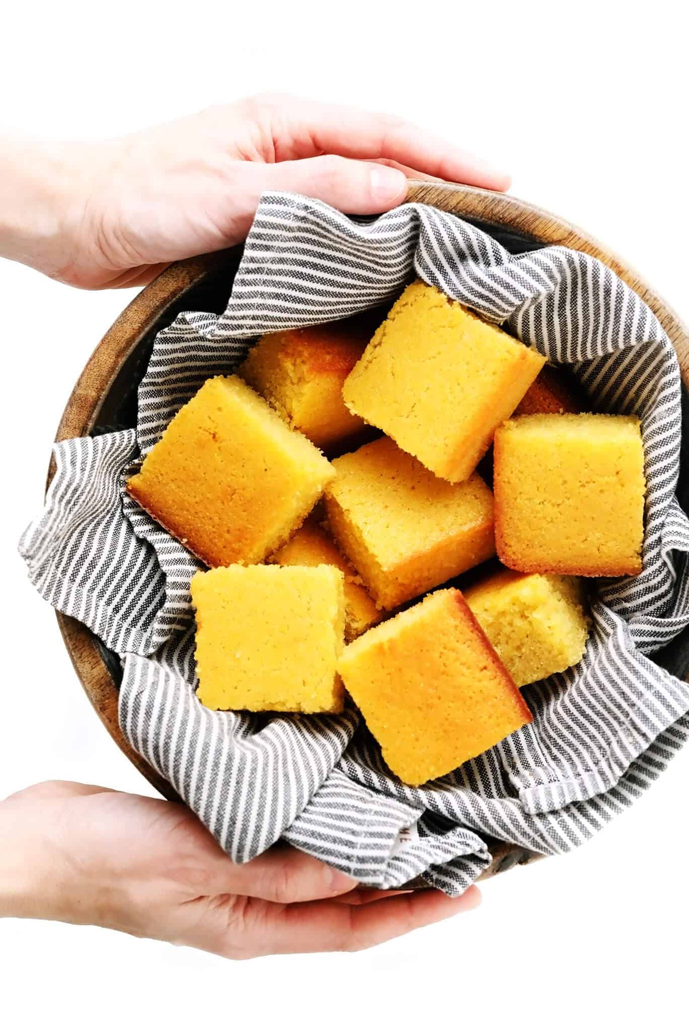 This amazing homemade cornbread recipe is lightly sweetened with honey, made extra moist with buttermilk, and tastes so buttery and delicious! Easy to make in a basic baking dish or cast iron skillet, or you can use this batter to make cornbread muffins. And perfect for serving with soup, chili, dressing/stuffing, or whatever sounds good! | gimmesomeoven.com #cornbread #bread #healthy #skillet #side #homemade #vegetarian #glutenfree Bowl of Homemade Cornbread Squares