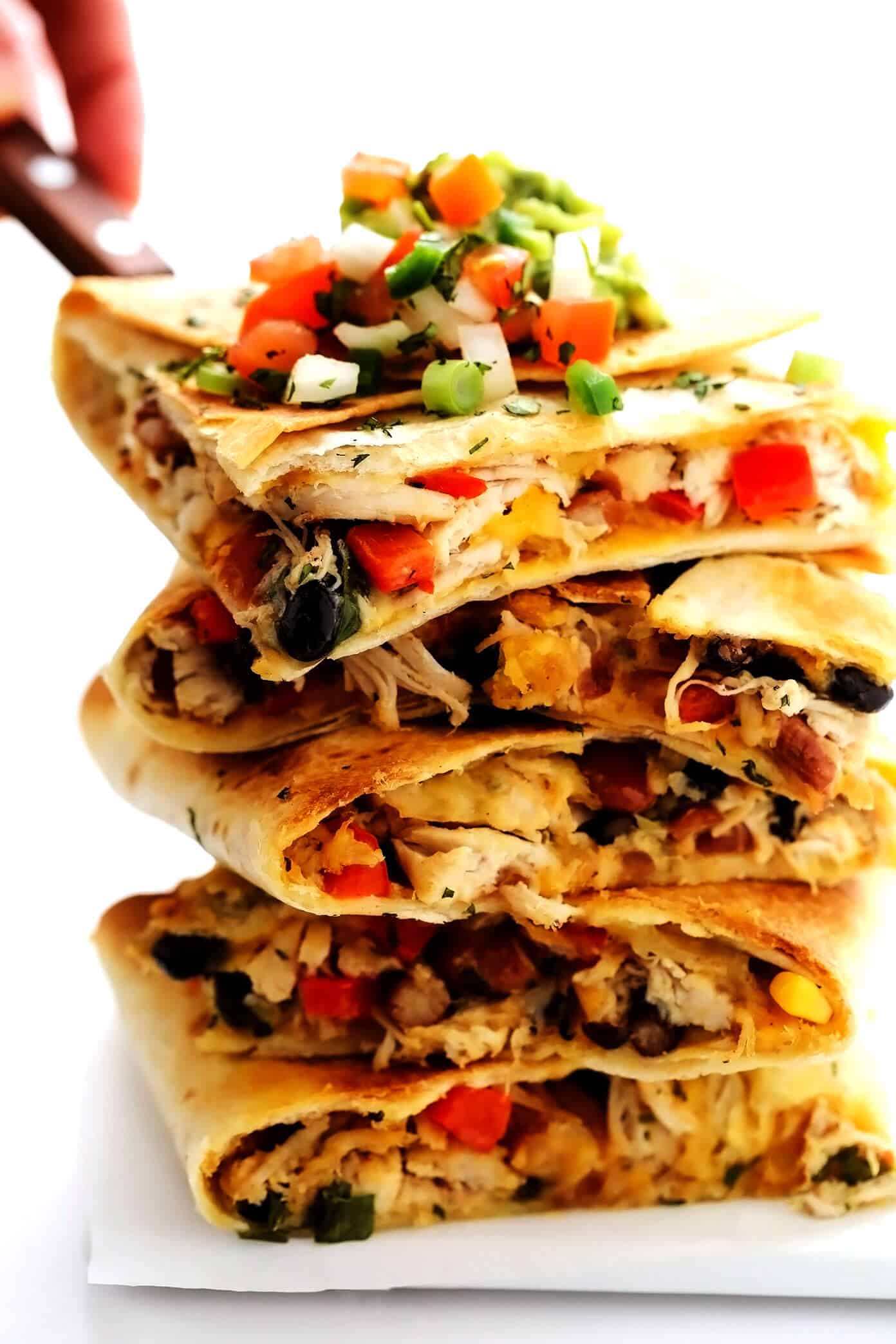 This party-sized chicken sheet pan quesadilla recipe is filled with a zesty mix of cheese, beans, veggies and baked up in a large sheet pan to feed a crowd. Serve as an appetizer, dinner entrée or game day snack with guacamole, salsa, sour cream or any of your favorite dips and enjoy! | gimmesomeoven.com #chicken #quesadilla #mexican #gameday #dinner #party #appetizer #cheese Layered Chicken Sheet Pan Quesadilla Slices
