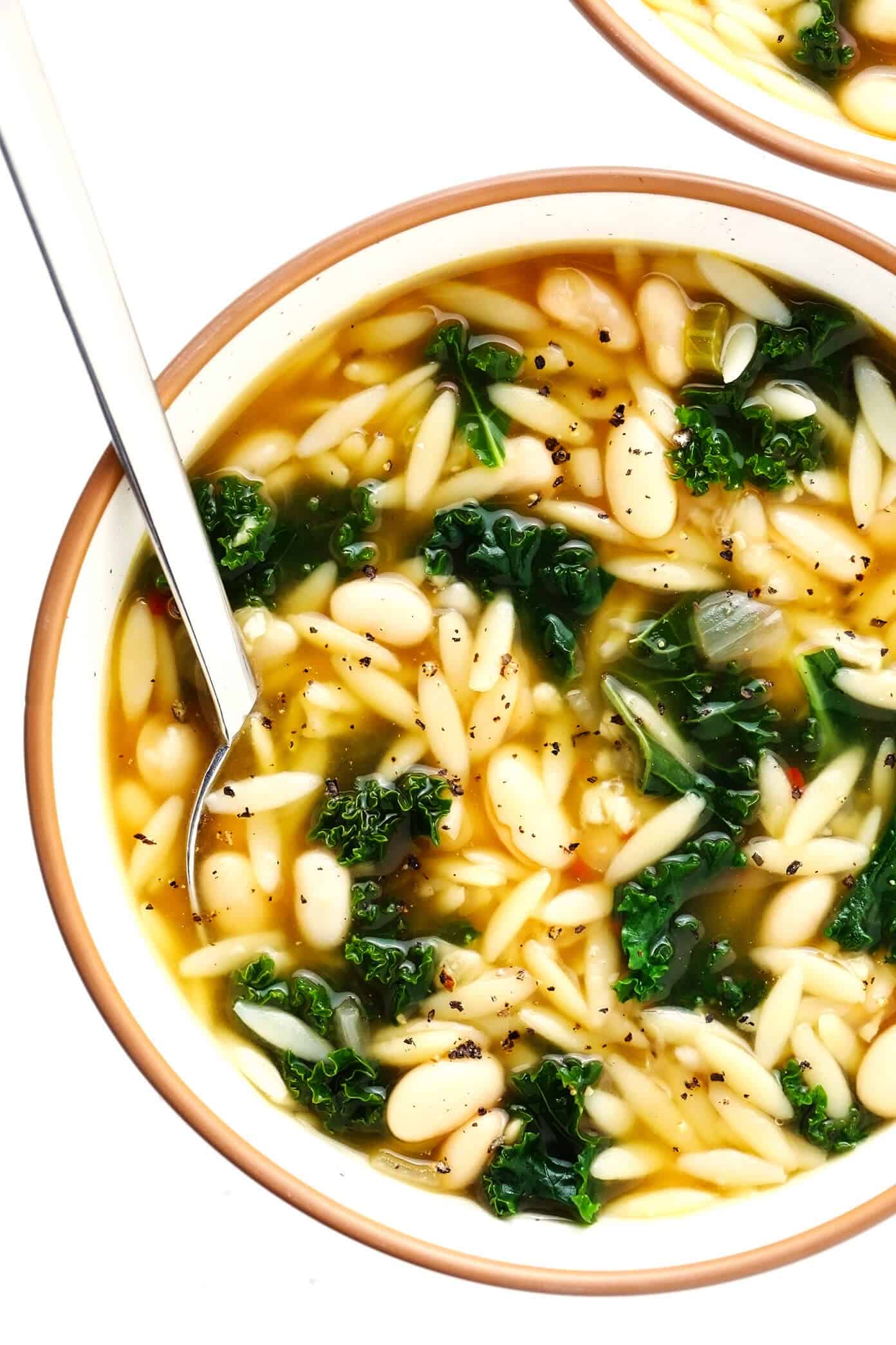 This simple Kale, White Bean and Orzo Soup is made with a cozy lemony-rosemary broth, topped with Parmesan cheese, and ready to go in just 30 minutes! A great vegetarian dinner recipe, or feel free to add a protein (chicken, bacon or sausage) if you'd like! | gimmesomeoven.com #soup #orzo #kale #bean #vegetarian #vegan #dinner #healthy Kale and Orzo Soup in Bowls