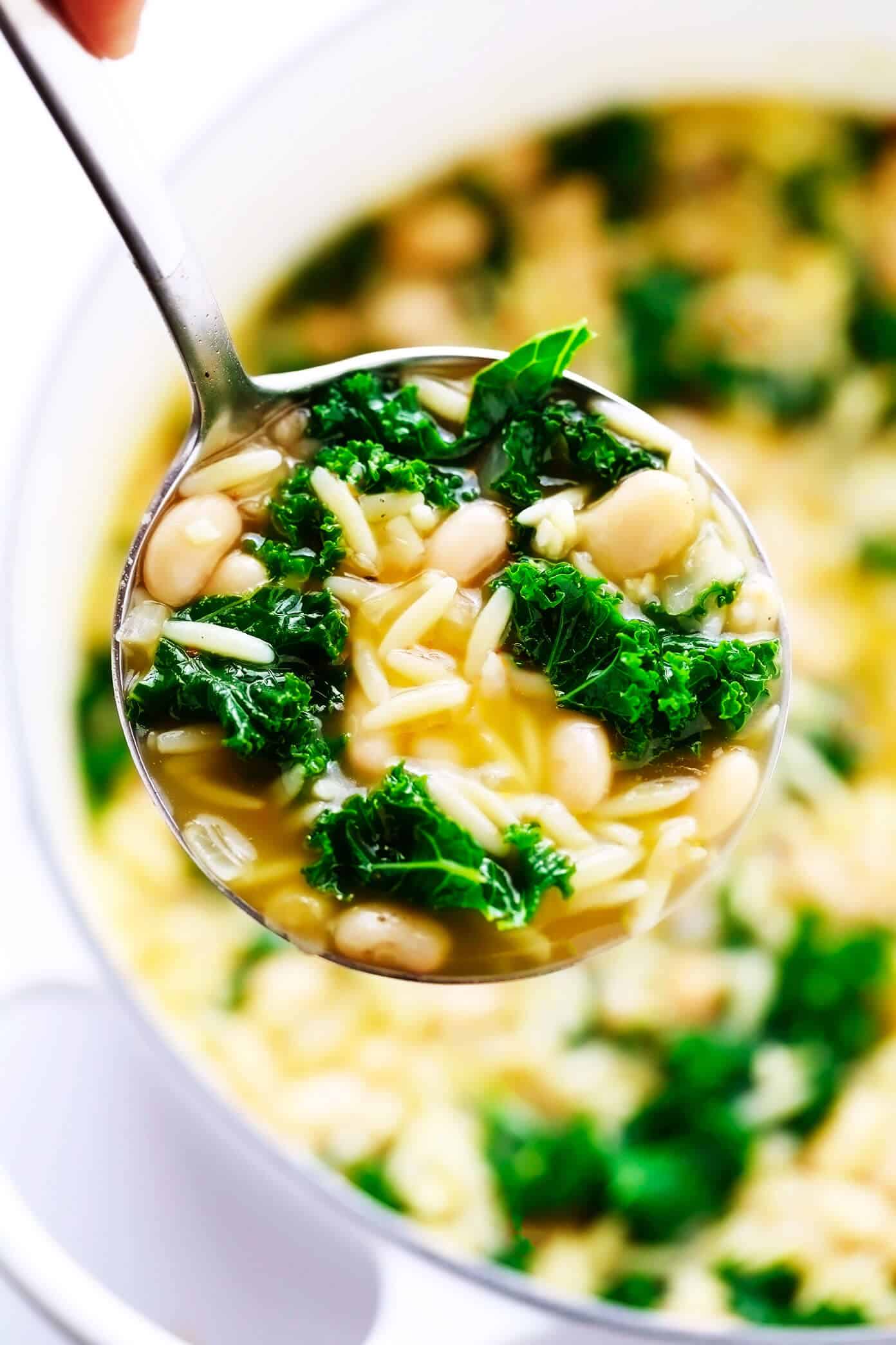 This simple Kale, White Bean and Orzo Soup is made with a cozy lemony-rosemary broth, topped with Parmesan cheese, and ready to go in just 30 minutes! A great vegetarian dinner recipe, or feel free to add a protein (chicken, bacon or sausage) if you'd like! | gimmesomeoven.com #soup #orzo #kale #bean #vegetarian #vegan #dinner #healthy Kale and White Bean Soup in Ladle