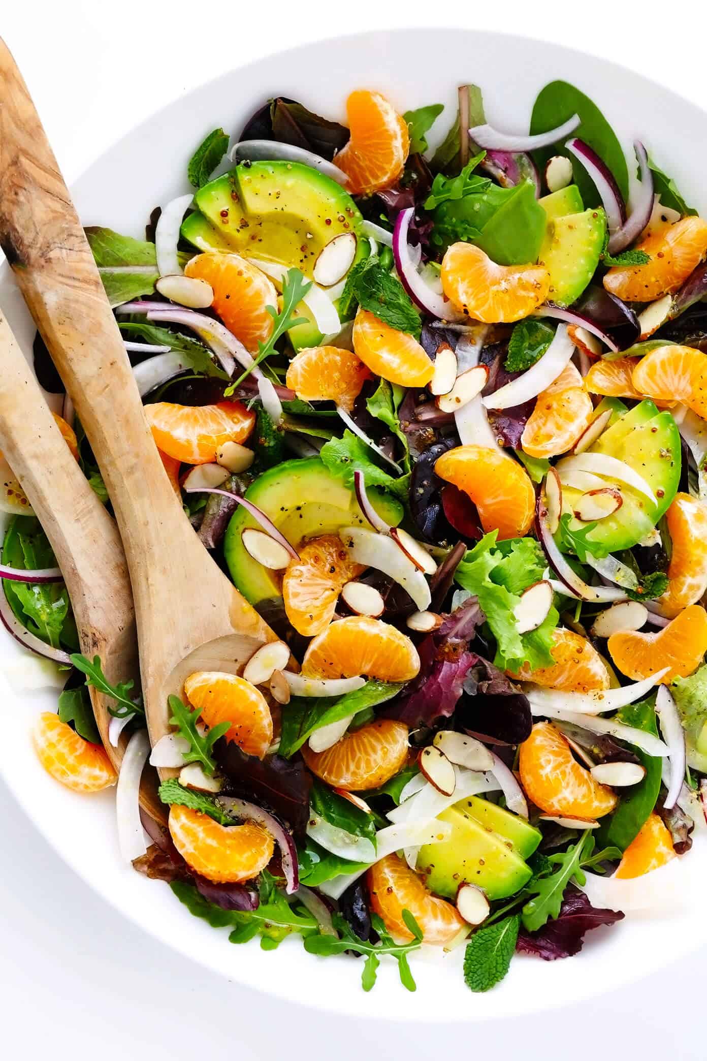 This Orange, Fennel and Avocado Salad recipe is quick and easy to make with fresh spring greens and mint, fresh clementines, toasted almonds, and a quick honey-citrus dressing. It's naturally vegan, vegetarian and gluten-free, but feel free to add in an extra protein (such as salmon, chicken or shrimp) if you'd like! | gimmesomeoven.com #salad #orange #citrus #avocado #healthy #glutenfree #vegan #vegetarian #dinner #winter Orange, Fennel and Avocado Salad in Bowl