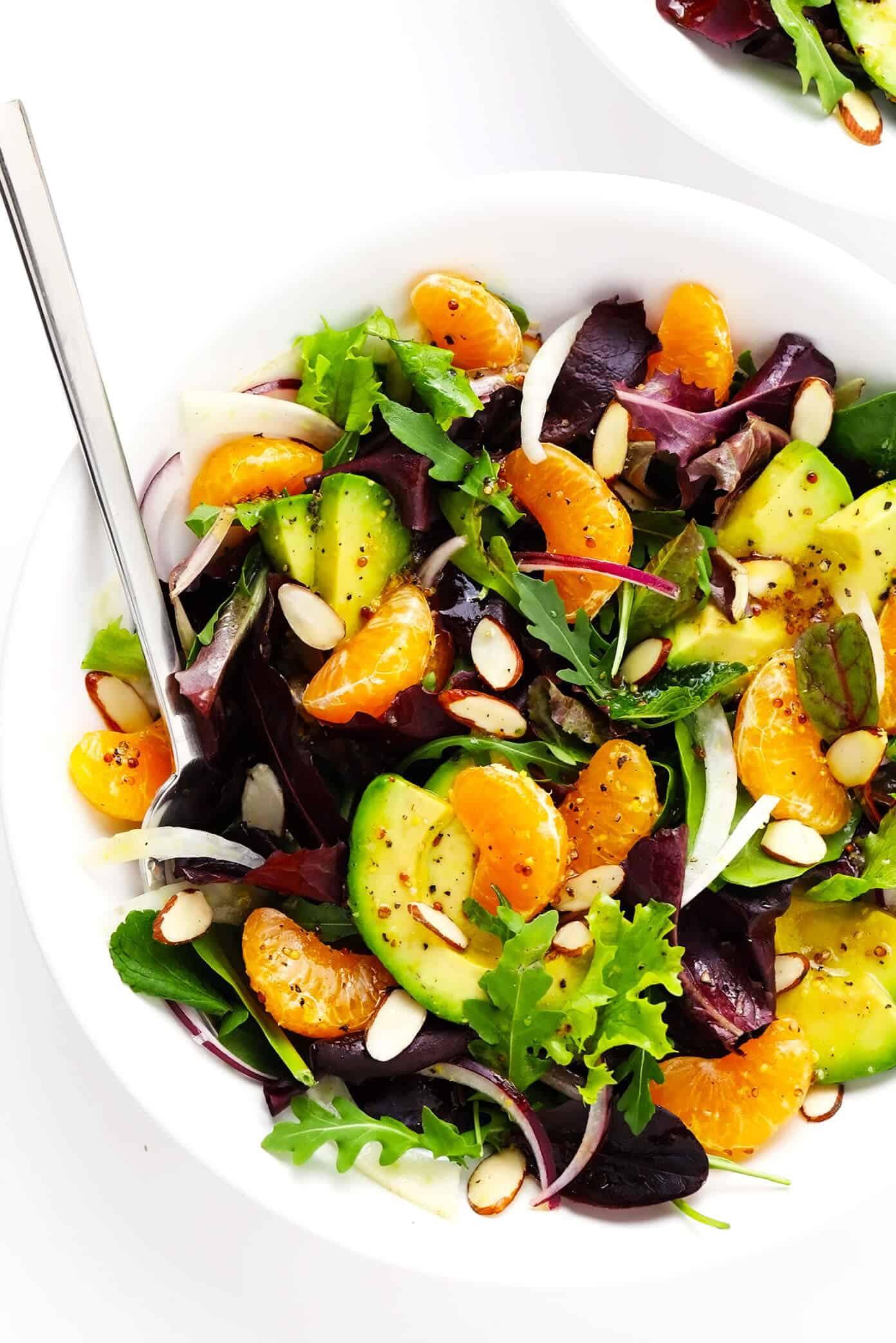 This Orange, Fennel and Avocado Salad recipe is quick and easy to make with fresh spring greens and mint, fresh clementines, toasted almonds, and a quick honey-citrus dressing. It's naturally vegan, vegetarian and gluten-free, but feel free to add in an extra protein (such as salmon, chicken or shrimp) if you'd like! | gimmesomeoven.com #salad #orange #citrus #avocado #healthy #glutenfree #vegan #vegetarian #dinner #winter Orange, Fellen and Avocado Salad in Serving Bowl with Almonds