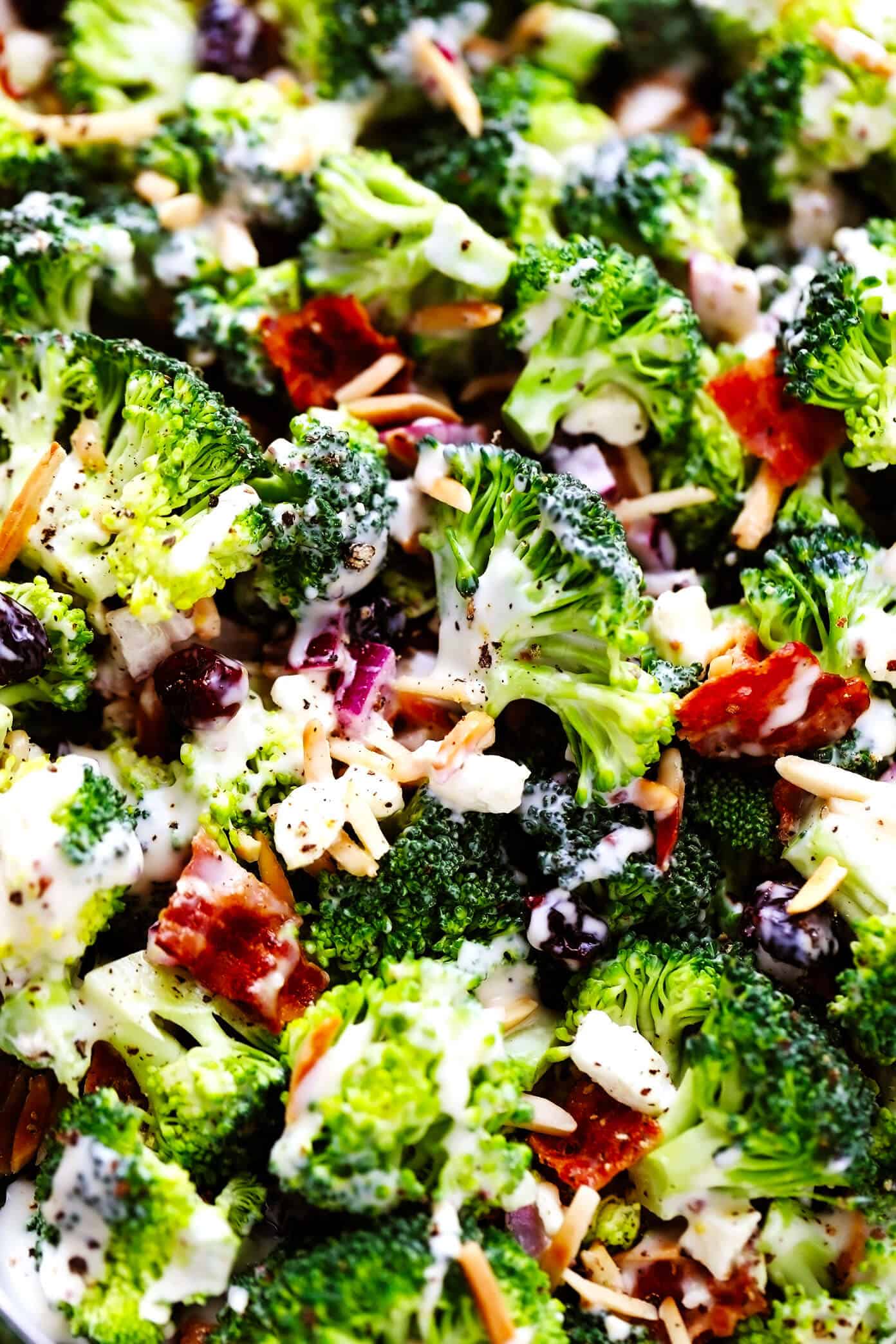 This classic broccoli salad recipe is made with fresh broccoli florets, crispy bacon, dried cranberries, toasted almonds, red onion, feta cheese, and a lightened-up creamy dressing. It's the perfect make-ahead side dish for picnics and potlucks and is always a crowd fave! | gimmesomeoven.com Closeup of Broccoli Salad with Bacon and Feta Cheese