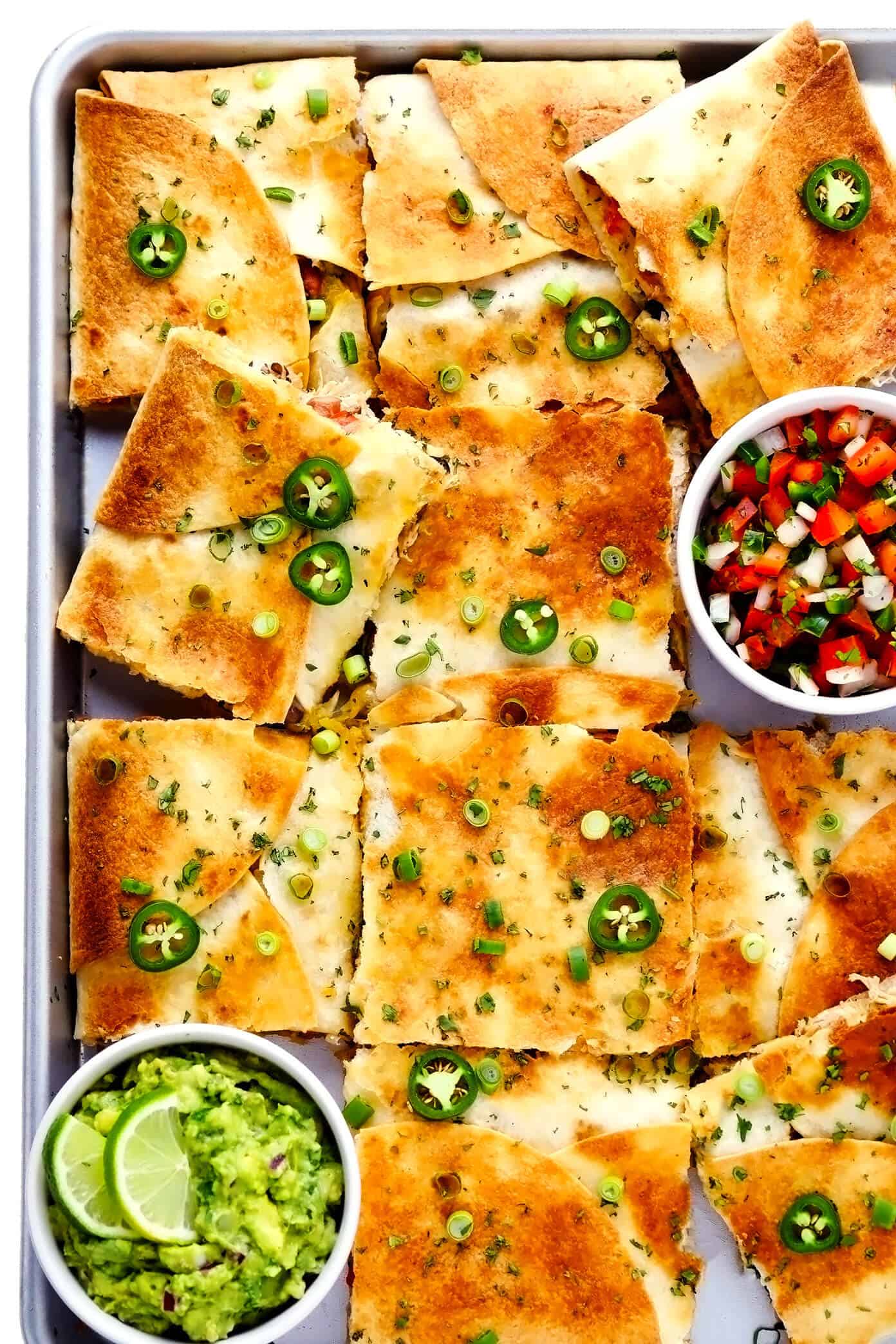 This party-sized chicken sheet pan quesadilla recipe is filled with a zesty mix of cheese, beans, veggies and baked up in a large sheet pan to feed a crowd. Serve as an appetizer, dinner entrée or game day snack with guacamole, salsa, sour cream or any of your favorite dips and enjoy! | gimmesomeoven.com #chicken #quesadilla #mexican #gameday #dinner #party #appetizer #cheese Chicken Sheet Pan Quesadilla with Guacamole and Pico de Gallo