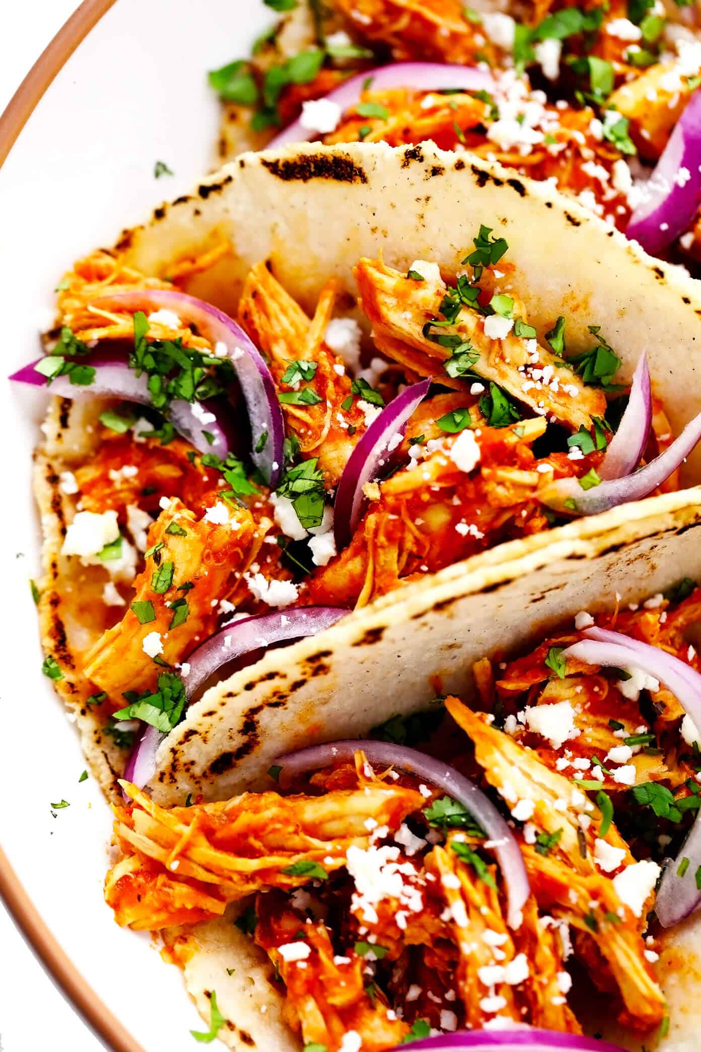 These Chicken Tinga Tacos are made with smoky chipotle chicken, served on warm corn tortillas, and loaded up with your favorite fresh toppings (such as avocado, cilantro, pickled red onions, cheese and more). Feel free to add refried beans or guacamole too, if you'd like. Always a delicious Mexican dinner recipe, and one that's ready to go in just over 30 minutes! | gimmesomeoven.com Chicken Tinga Tacos Closeup