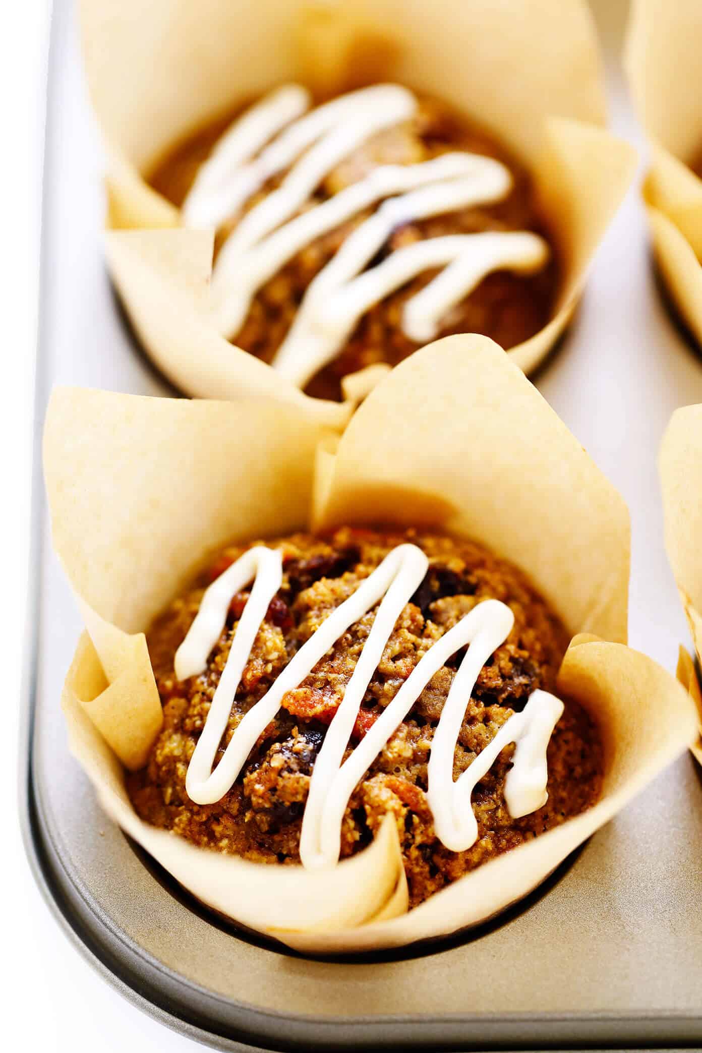 These Healthy Carrot Cake Muffins are easy to make with oatmeal, lots of fresh carrots, maple syrup, and a handful of other simple and healthy ingredients. Feel free to top them with a lightened-up cream cheese frosting drizzle, and add in raisins, nuts and/or coconut if you'd like too. Perfect for a feel-good breakfast, snack or dessert! | gimmesomeoven.com #carrot #cake #muffins #healthy #creamcheese #frosting #icing #breakfast #snack #vegetarian #glutenfree #easter #spring Closeup Carrot Cake Muffins with Cream Cheese Glaze