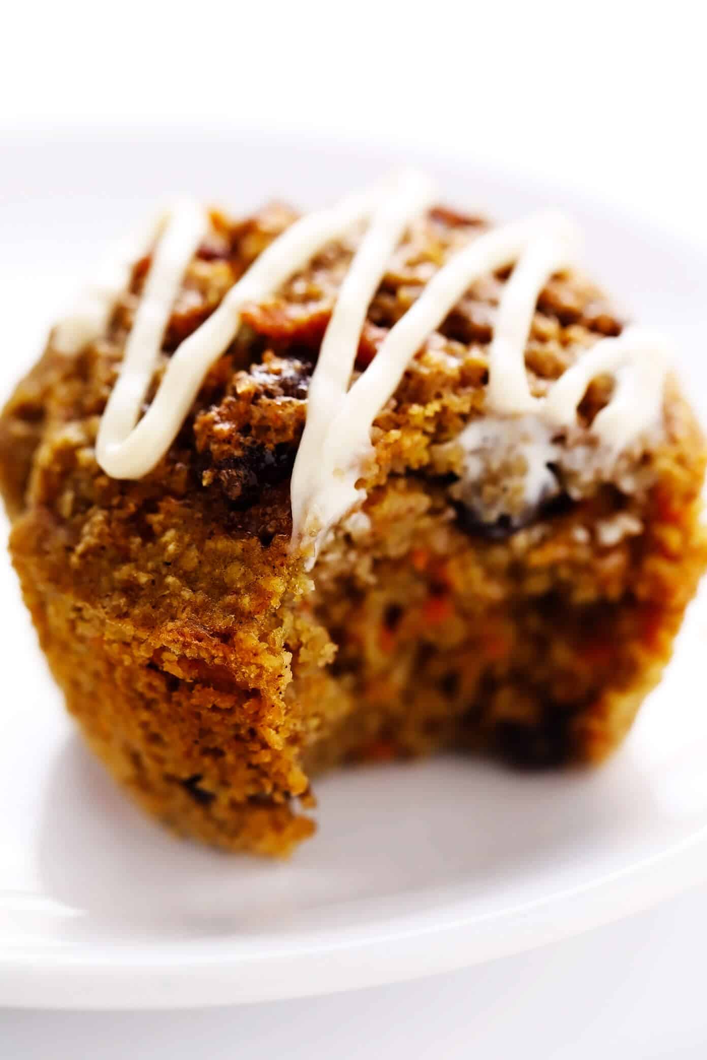 These Healthy Carrot Cake Muffins are easy to make with oatmeal, lots of fresh carrots, maple syrup, and a handful of other simple and healthy ingredients. Feel free to top them with a lightened-up cream cheese frosting drizzle, and add in raisins, nuts and/or coconut if you'd like too. Perfect for a feel-good breakfast, snack or dessert! | gimmesomeoven.com #carrot #cake #muffins #healthy #creamcheese #frosting #icing #breakfast #snack #vegetarian #glutenfree #easter #spring Healthy Carrot Cake Muffin with Bite Taken Out