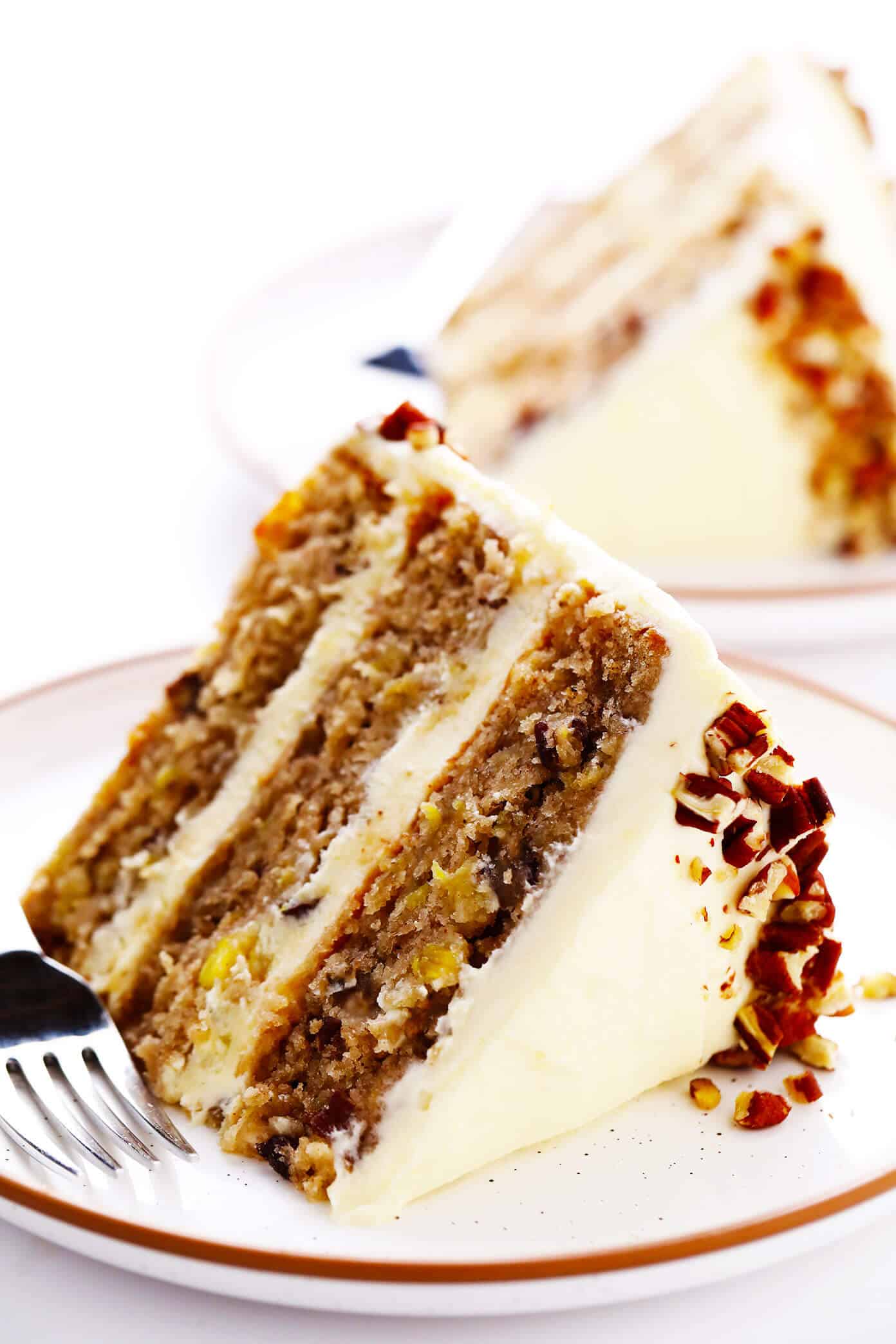 This delicious hummingbird cake recipe features ultra-moist pineapple banana cake layered with rich cream cheese frosting and a sprinkle of toasted pecans. It's the perfect dessert for spring, summer, or Easter and it's always a crowd fave! | gimmesomeoven.com #cake #dessert #hummingbird #jamaican #southern #creamcheese #frosting #icing #banana #pineapple #pecan Hummingbird Cake Slices with Cream Cheese Frosting