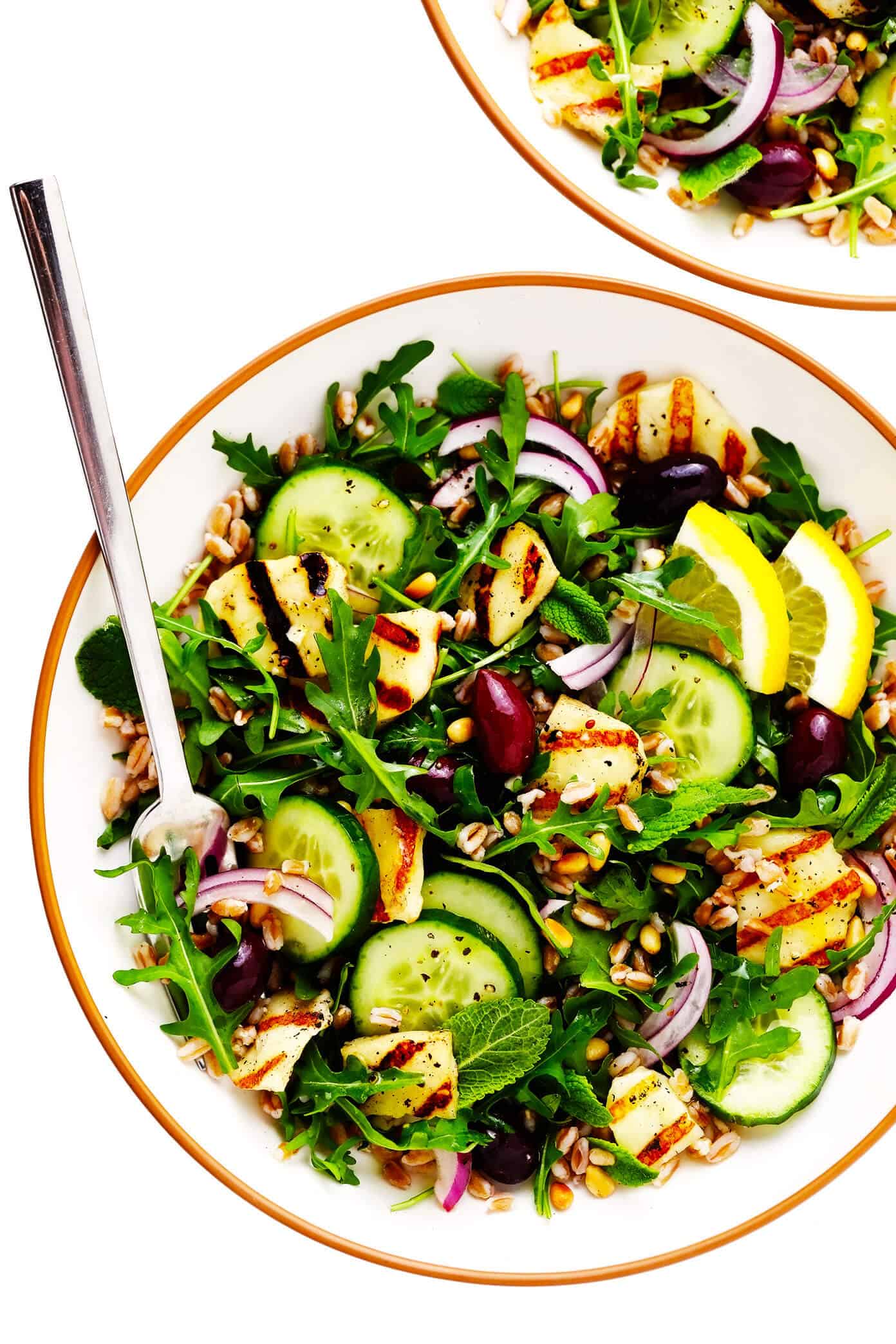 This Mediterranean-inspired grilled halloumi salad is easy to make with pan-grilled halloumi cheese, chewy farro, fresh cucumber and mint, and a zippy lemon dressing. It's the perfect side or entree salad to serve for dinner. And feel free to add in chicken, beef, shrimp or chickpeas if you'd like, too! | gimmesomeoven.com Grilled Halloumi Salad in Serving Bowls