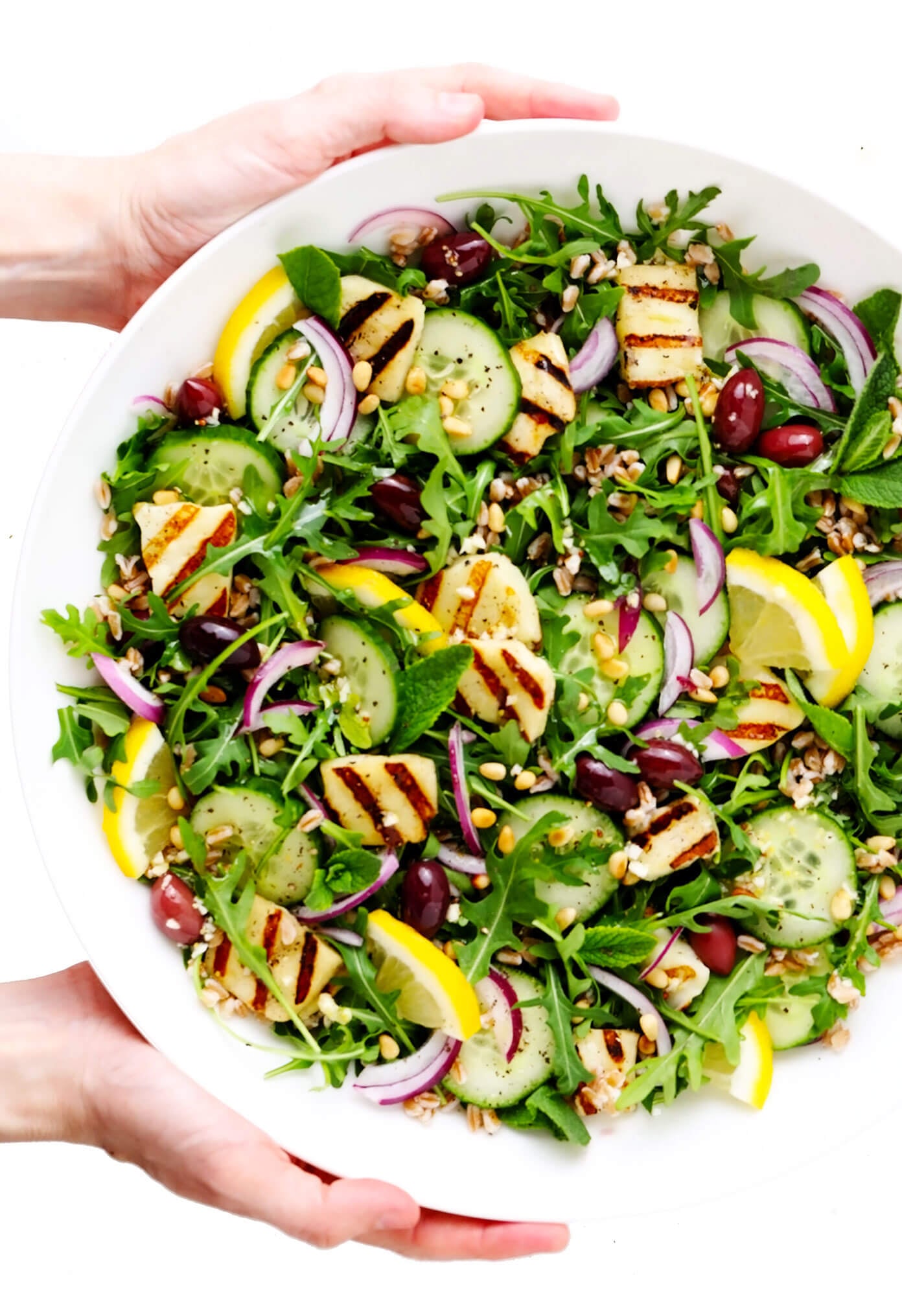 This Mediterranean-inspired grilled halloumi salad is easy to make with pan-grilled halloumi cheese, chewy farro, fresh cucumber and mint, and a zippy lemon dressing. It's the perfect side or entree salad to serve for dinner. And feel free to add in chicken, beef, shrimp or chickpeas if you'd like, too! | gimmesomeoven.com Grilled Halloumi Salad in Large Serving Bowl