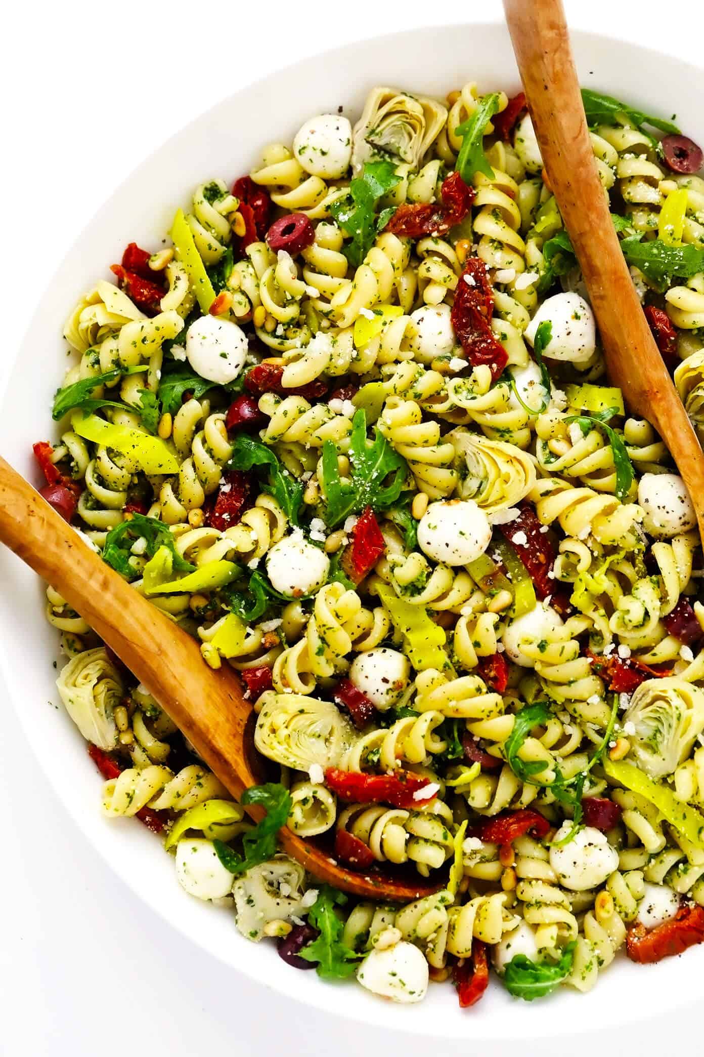 This Italian-inspired Pesto Pasta Salad recipe is loaded up with artichoke hearts, arugula, mozzarella, pepperoncini peppers, Kalamata olives, pine nuts and sprinkled with Parmesan. It's the perfect easy vegetarian side dish for summer grilling, parties and potlucks -- and easy to make gluten-free or vegan if you'd like too! | gimmesomeoven.com Pesto Pasta Salad