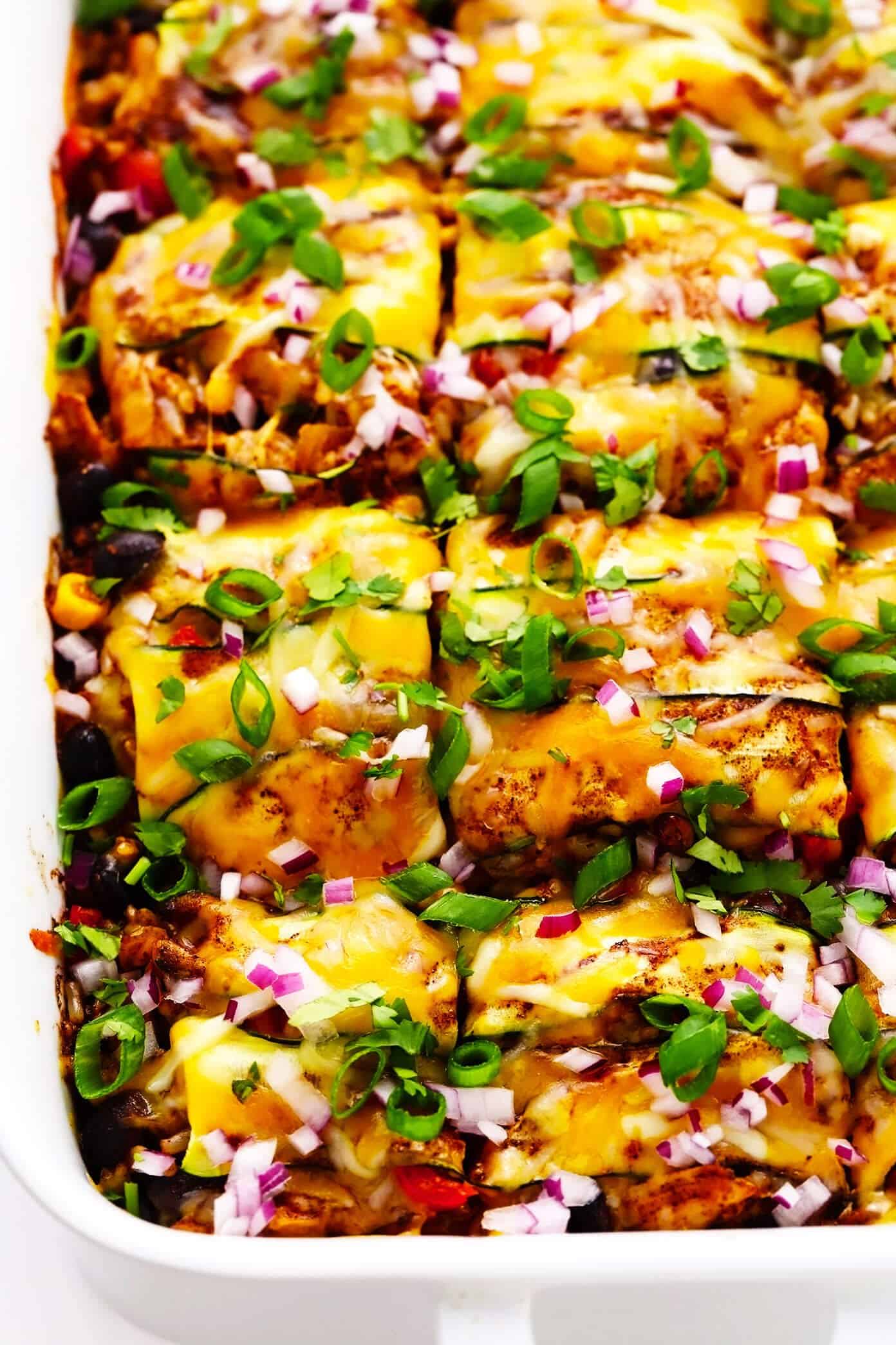 This Tex-Mex-inspired zucchini enchilada casserole is stacked (not rolled!) with layers of sliced zucchini, veggies, cheese, beans, rice and the most delicious homemade red enchilada sauce. It's naturally gluten-free and can be made with meat (chicken, beef, pork, chorizo, etc) or kept vegetarian. Serve it up for dinner with some avocado and enjoy! | gimmesomeoven.com Zucchini Enchilada Casserole