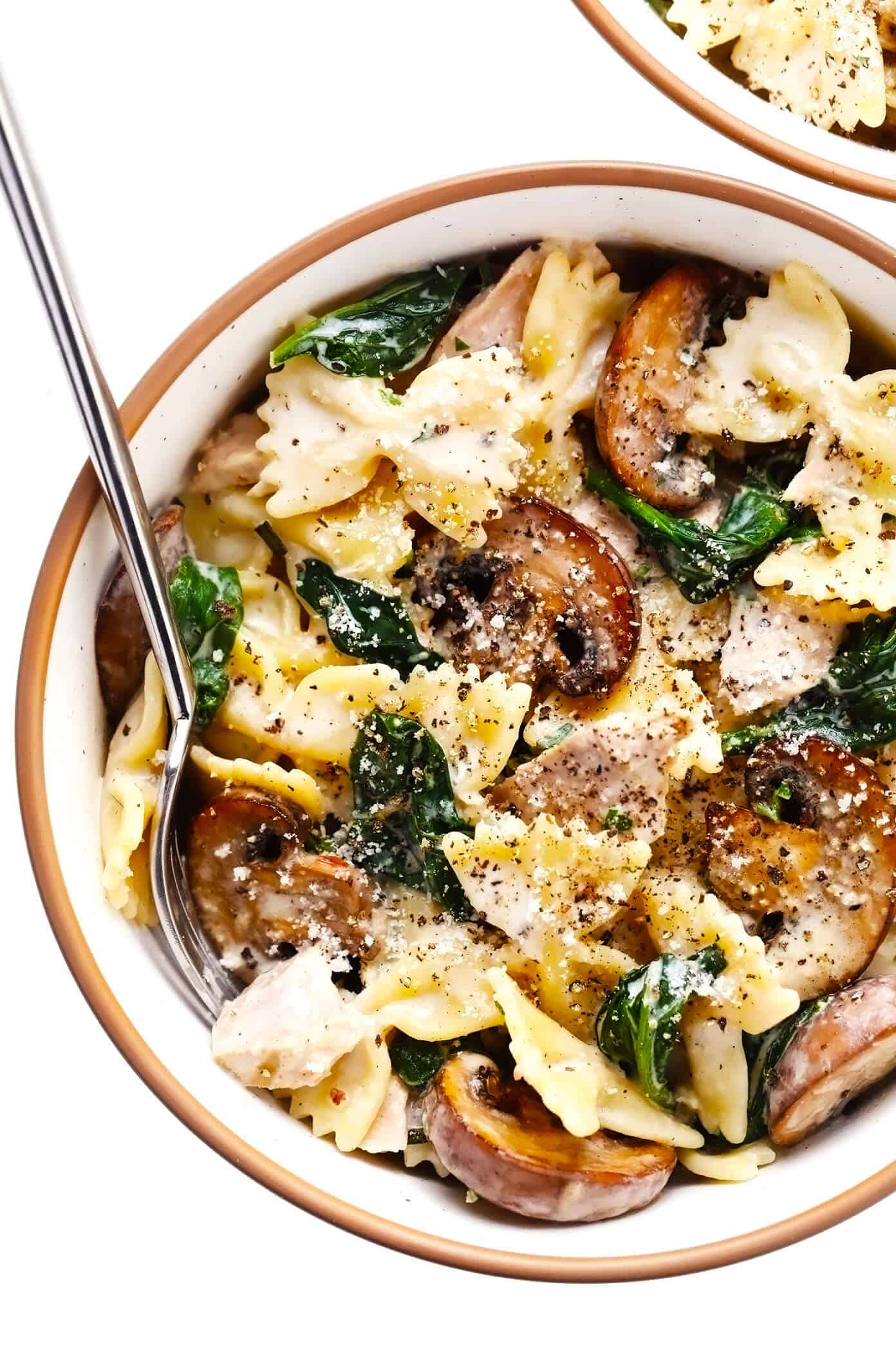 This creamy tuna mushroom pasta recipe is tossed with perfectly al dente pasta, sautéed mushrooms, tender spinach, canned tuna, and garlic lemon rosemary cream sauce. It's a super easy dinner recipe to make in just 30 minutes and taste SO delicious! | gimmesomeoven.com Creamy Tuna Mushroom Pasta in Serving Bowl with Parmesan and Black Pepper