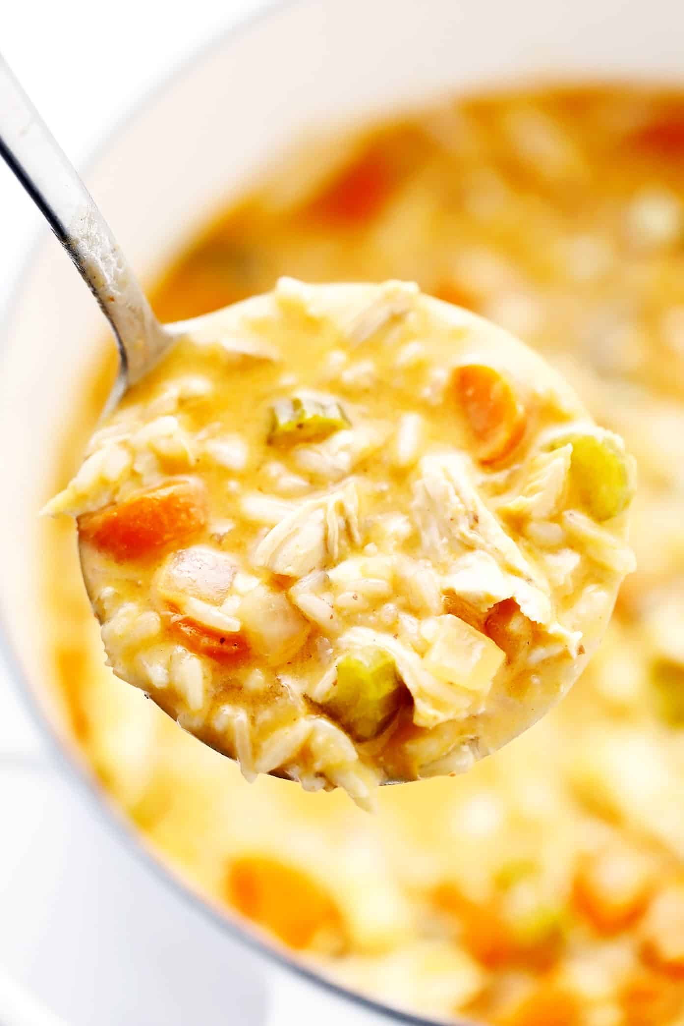 This creamy buffalo chicken and rice soup recipe is simmered with tender chicken, veggies, rice and a zesty blend of buffalo seasonings. Highly recommend topping with blue cheese and bacon too! Perfect for game day or easy weeknight dinner. Stovetop, Instant Pot and Crock-Pot options included. | gimmesomeoven.com Ladle closeup of buffalo chicken soup