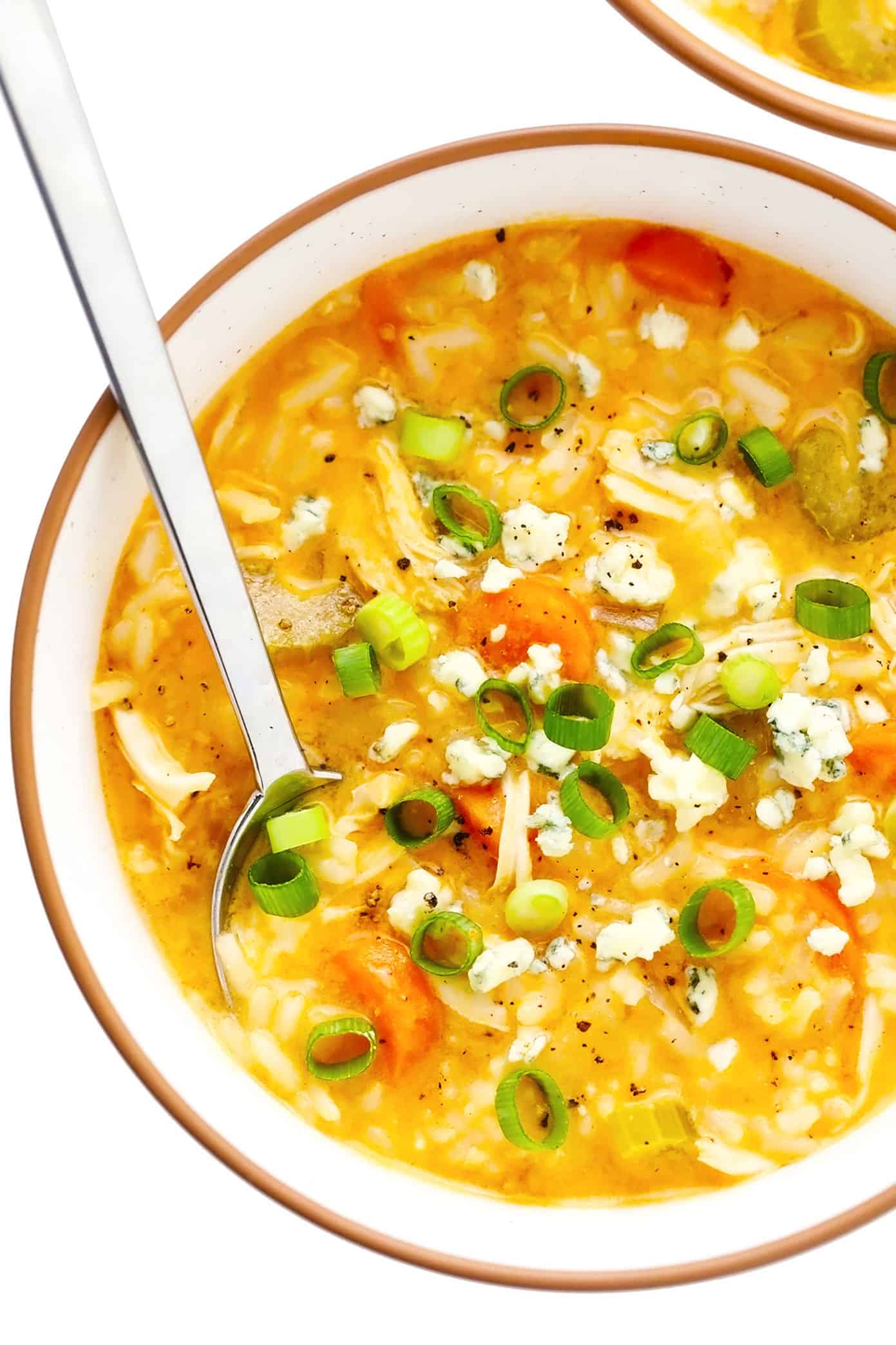 This creamy buffalo chicken and rice soup recipe is simmered with tender chicken, veggies, rice and a zesty blend of buffalo seasonings. Highly recommend topping with blue cheese and bacon too! Perfect for game day or easy weeknight dinner. Stovetop, Instant Pot and Crock-Pot options included. | gimmesomeoven.com Bowl of buffalo chicken and rice soup with blue cheese