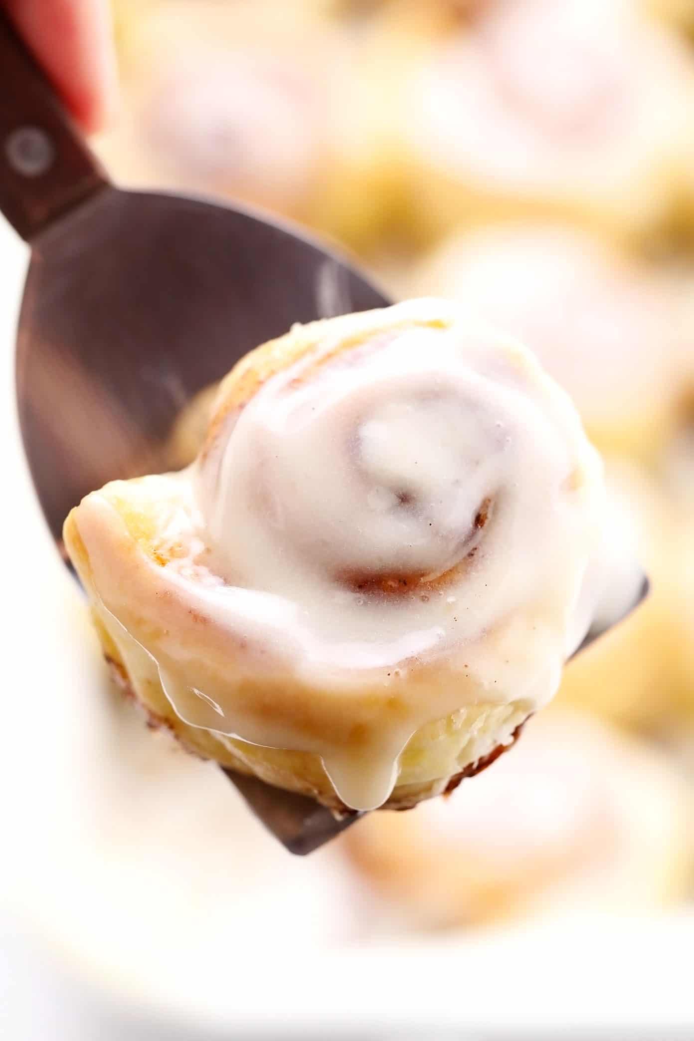 This shortcut puff pastry cinnamon rolls recipe is super fast and easy to prepare, topped with a dreamy cream cheese frosting, and irresistibly buttery, flaky and delicious. The perfect breakfast or brunch pastry when you need something quick! | gimmesomeoven.com Holding up a puff pastry cinnamon bun