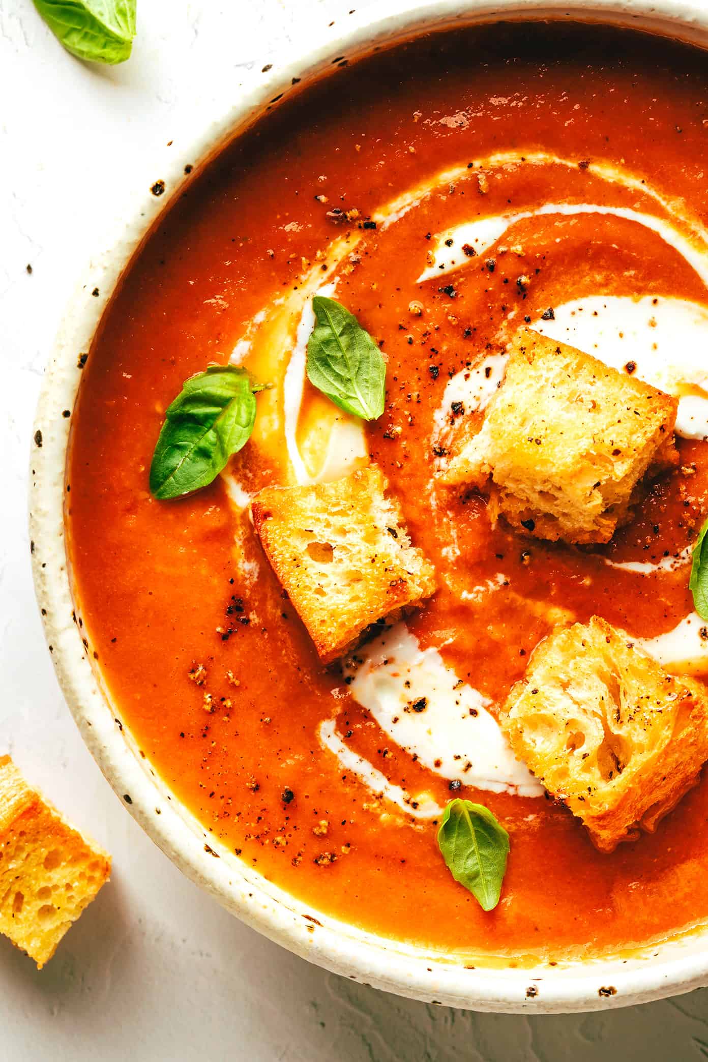 This roasted tomato soup recipe always tastes so fresh and flavorful and it's easy to make with a handful of simple ingredients. Feel free to add cream or croutons if you'd like! | gimmesomeoven.com Roasted tomato soup in bowl with basil, cream and croutons