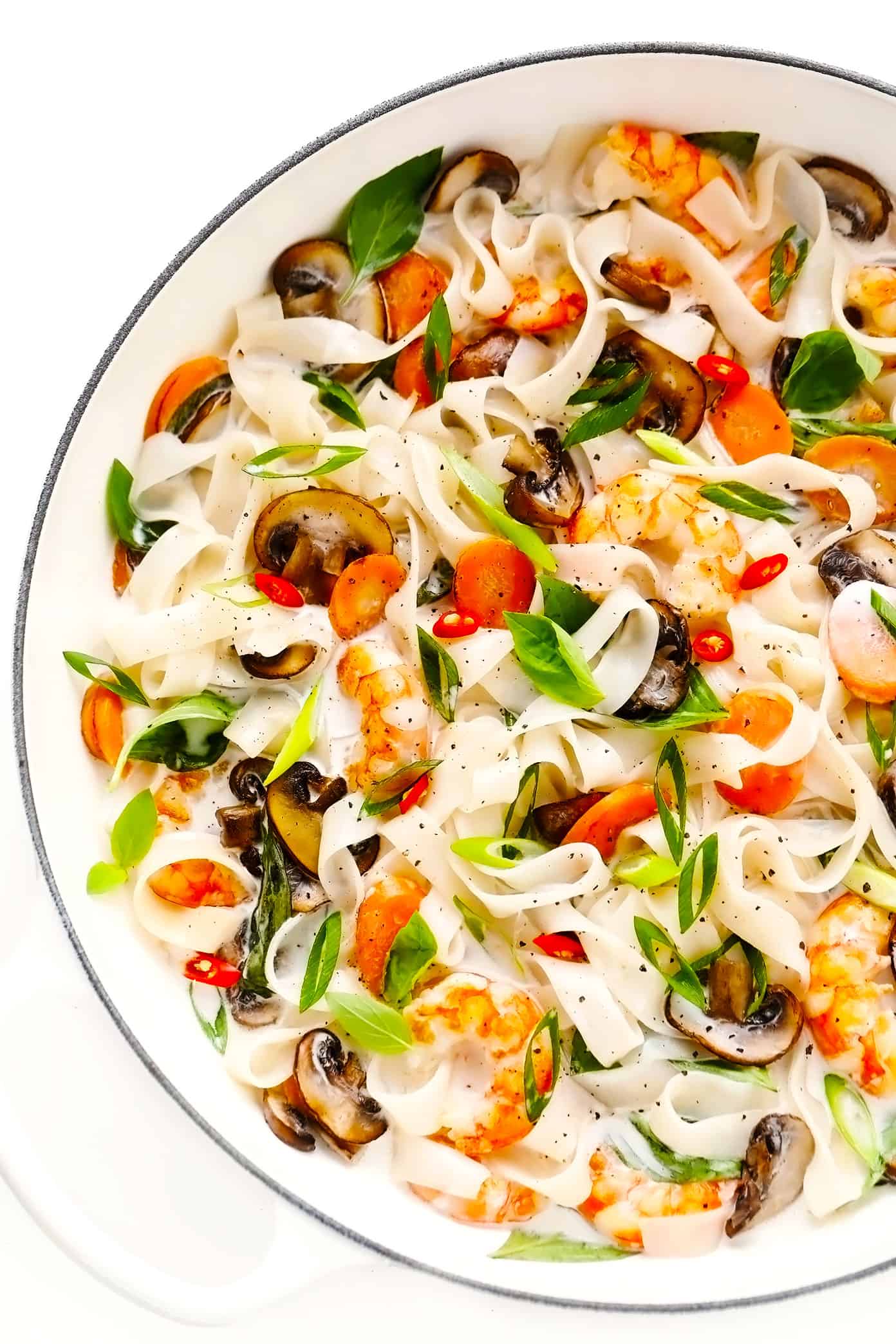 This Thai-inspired noodle stir-fry is tossed with fresh mushrooms and carrots, tender shrimp, and a zesty lemongrass ginger coconut sauce. Easy to make for dinner and full the best bright and citrusy flavors! Feel free to sub in chicken, beef, pork or tofu in place of the shrimp if you prefer. | gimmesomeoven.com Saute pan with lemongrass coconut noodles, shrimp, mushrooms and Thai basil