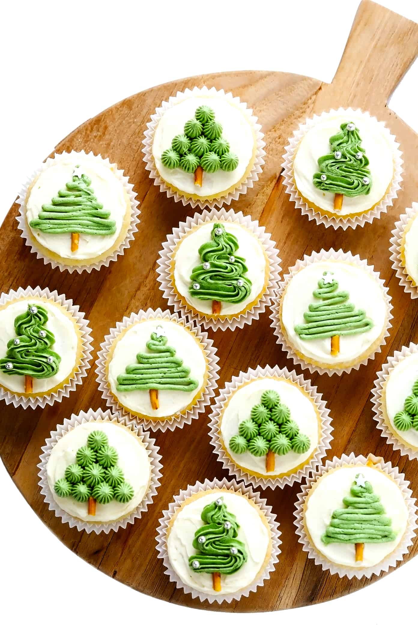 These cute Christmas cupcakes are made with soft and fluffy vanilla cupcakes, a simple vanilla buttercream frosting, and whatever fun sprinkles or toppings you choose. Decorating instructions and supply list included too for this fun holiday dessert! | gimmesomeoven.com Christmas Tree Cupcakes on Wooden Tray