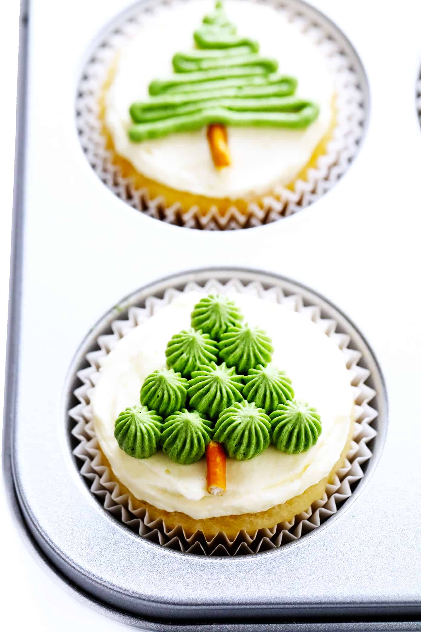 These cute Christmas cupcakes are made with soft and fluffy vanilla cupcakes, a simple vanilla buttercream frosting, and whatever fun sprinkles or toppings you choose. Decorating instructions and supply list included too for this fun holiday dessert! | gimmesomeoven.com Easy Christmas Tree Cupcakes in Baking Pan
