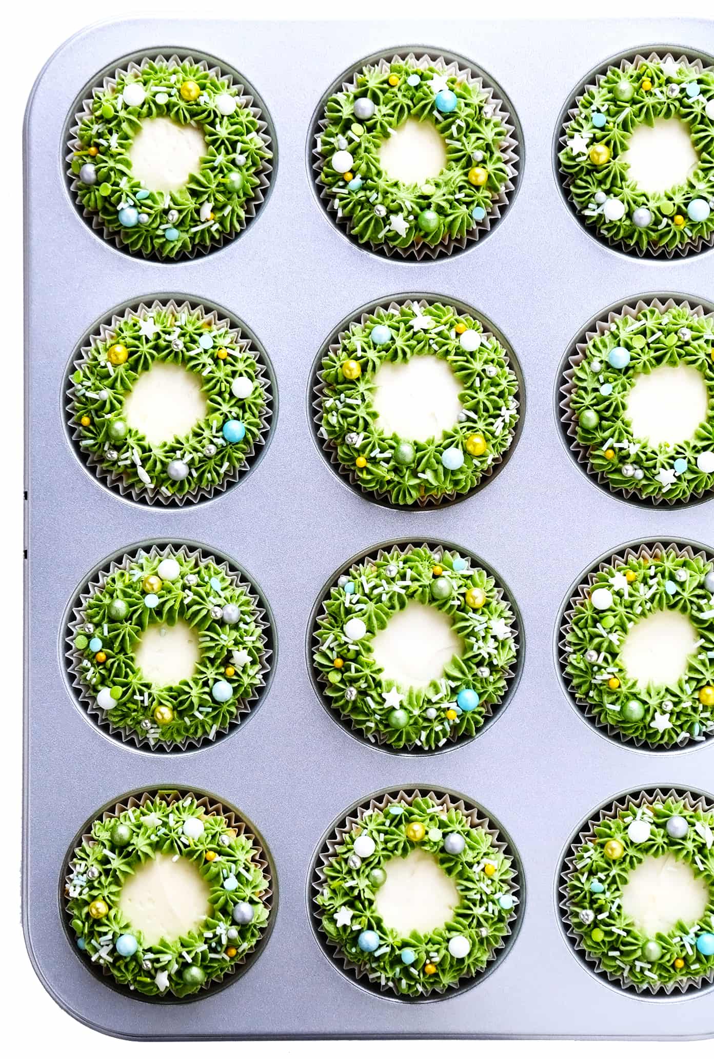 These cute Christmas cupcakes are made with soft and fluffy vanilla cupcakes, a simple vanilla buttercream frosting, and whatever fun sprinkles or toppings you choose. Decorating instructions and supply list included too for this fun holiday dessert! | gimmesomeoven.com Christmas Wreath Cupcakes