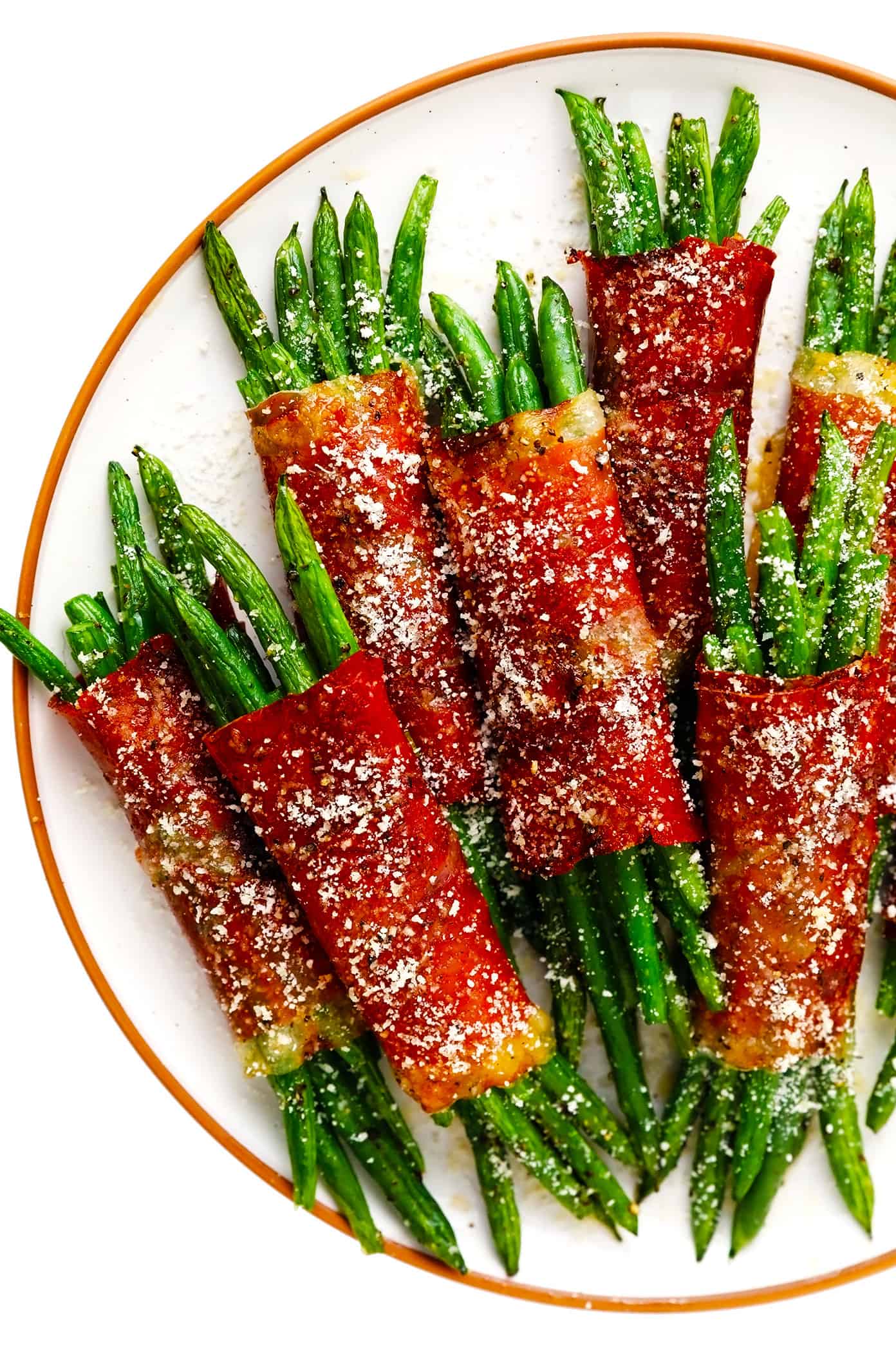These green bean bundles are tossed with rosemary honey garlic butter, wrapped in prosciutto, and sprinkled with freshly-grated Parmesan. Super easy to make ahead and only 10 minutes needed to bake. Perfect for your Thanksgiving, Christmas, or holiday menu...yet also easy enough for a fun weeknight side dish. | gimmesomeoven.com Roasted Green Bean Bundles with Prosciutto on Serving Plate