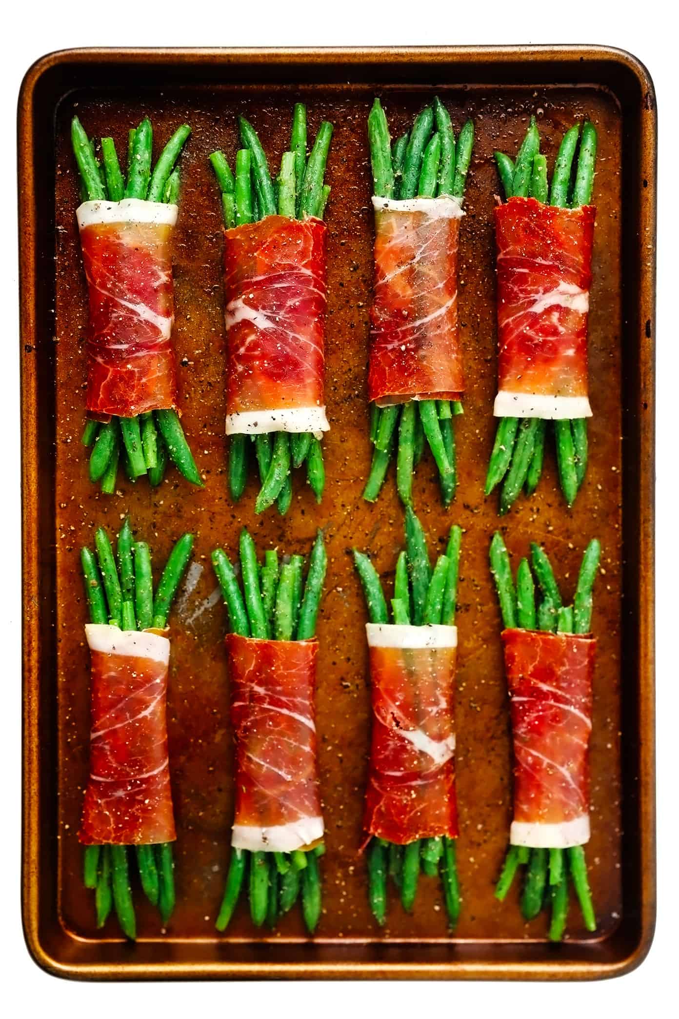 These green bean bundles are tossed with rosemary honey garlic butter, wrapped in prosciutto, and sprinkled with freshly-grated Parmesan. Super easy to make ahead and only 10 minutes needed to bake. Perfect for your Thanksgiving, Christmas, or holiday menu...yet also easy enough for a fun weeknight side dish. | gimmesomeoven.com Prosciutto-Wrapped Green Bean Bundles Unbaked