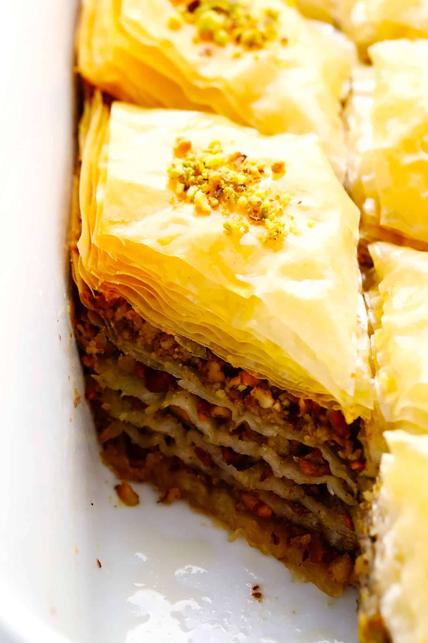 A step-by-step guide (and video) for how to make homemade baklava with perfectly crispy golden layers of buttery phyllo, pistachios and walnuts (or your choice of nuts), and lovely orange honey syrup. Always such a delicious treat! | gimmesomeoven.com Closeup of pistachio and walnut baklava