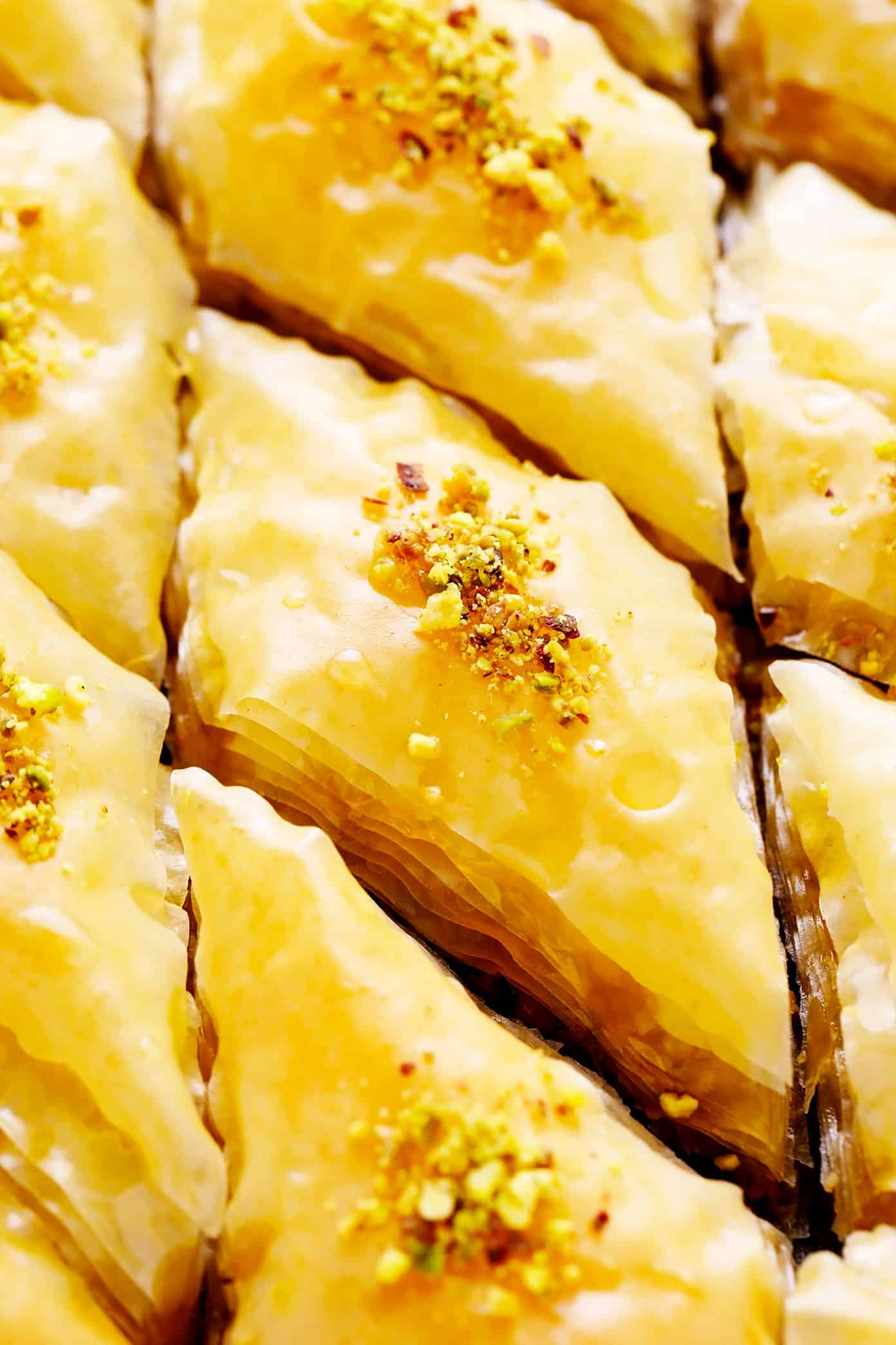 A step-by-step guide (and video) for how to make homemade baklava with perfectly crispy golden layers of buttery phyllo, pistachios and walnuts (or your choice of nuts), and lovely orange honey syrup. Always such a delicious treat! | gimmesomeoven.com Closeup of walnut and pistachio baklava