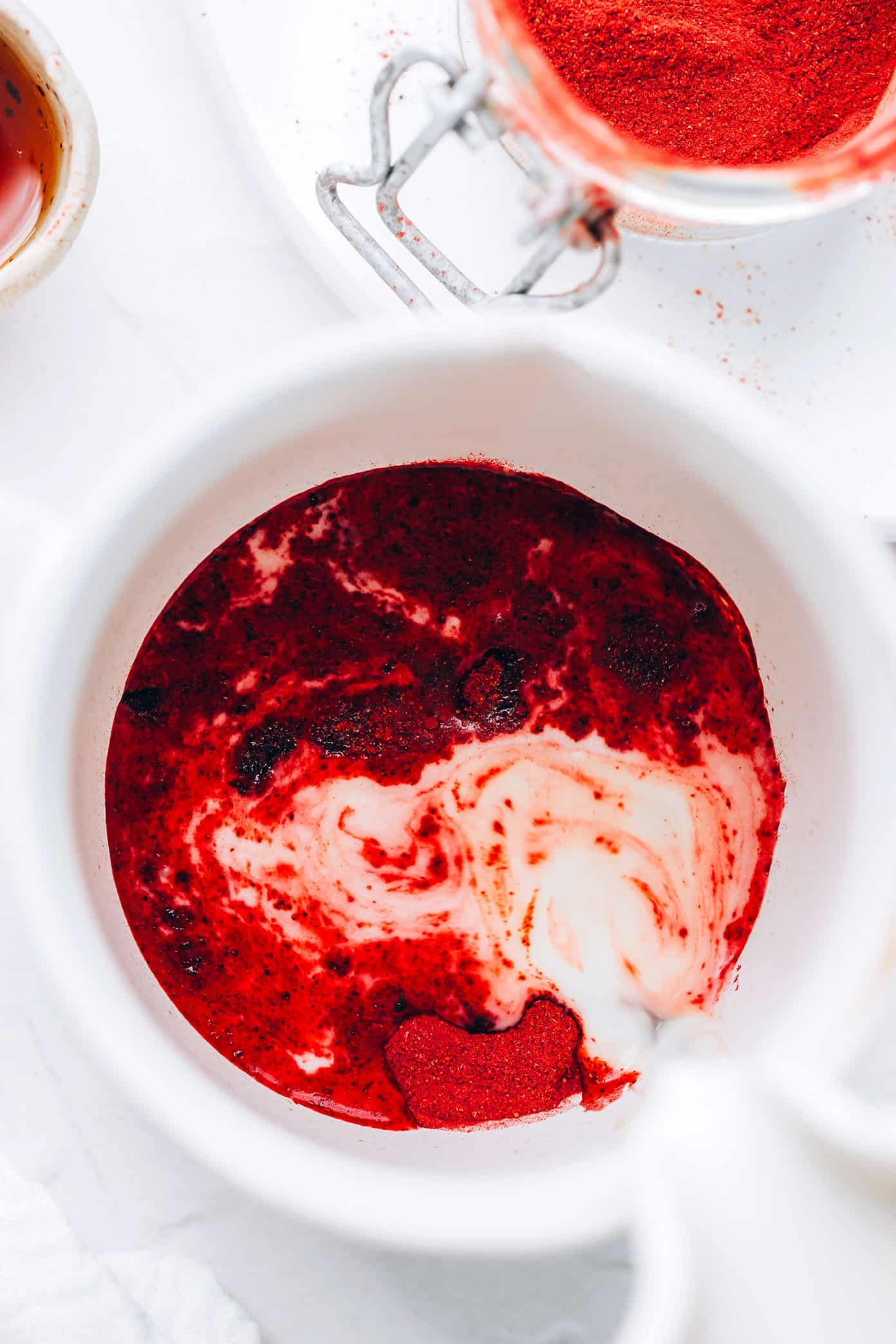 This nutrient-rich pink latte recipe is easy to make hot or iced and features a cozy mix of beetroot powder and warming spices (cardamom, cinnamon, ginger and cloves), your choice of milk and a hint of sweetener. Such cozy, vibrant and delicious drink! | gimmesomeoven.com Pouring frothed milk into a pink latte mix