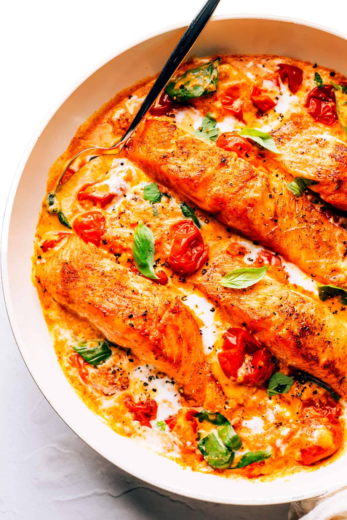 This Salmon in Burst Tomato Sauce is incredibly easy to make and simmered with the most delicious Italian-inspired garlicky cherry tomato basil cream sauce. Easy to make in 30 minutes, and delicious served for dinner with crusty bread, pasta, or rice and a simple side salad. | gimmesomeoven.com Salmon with Burst Tomato Sauce in Pan
