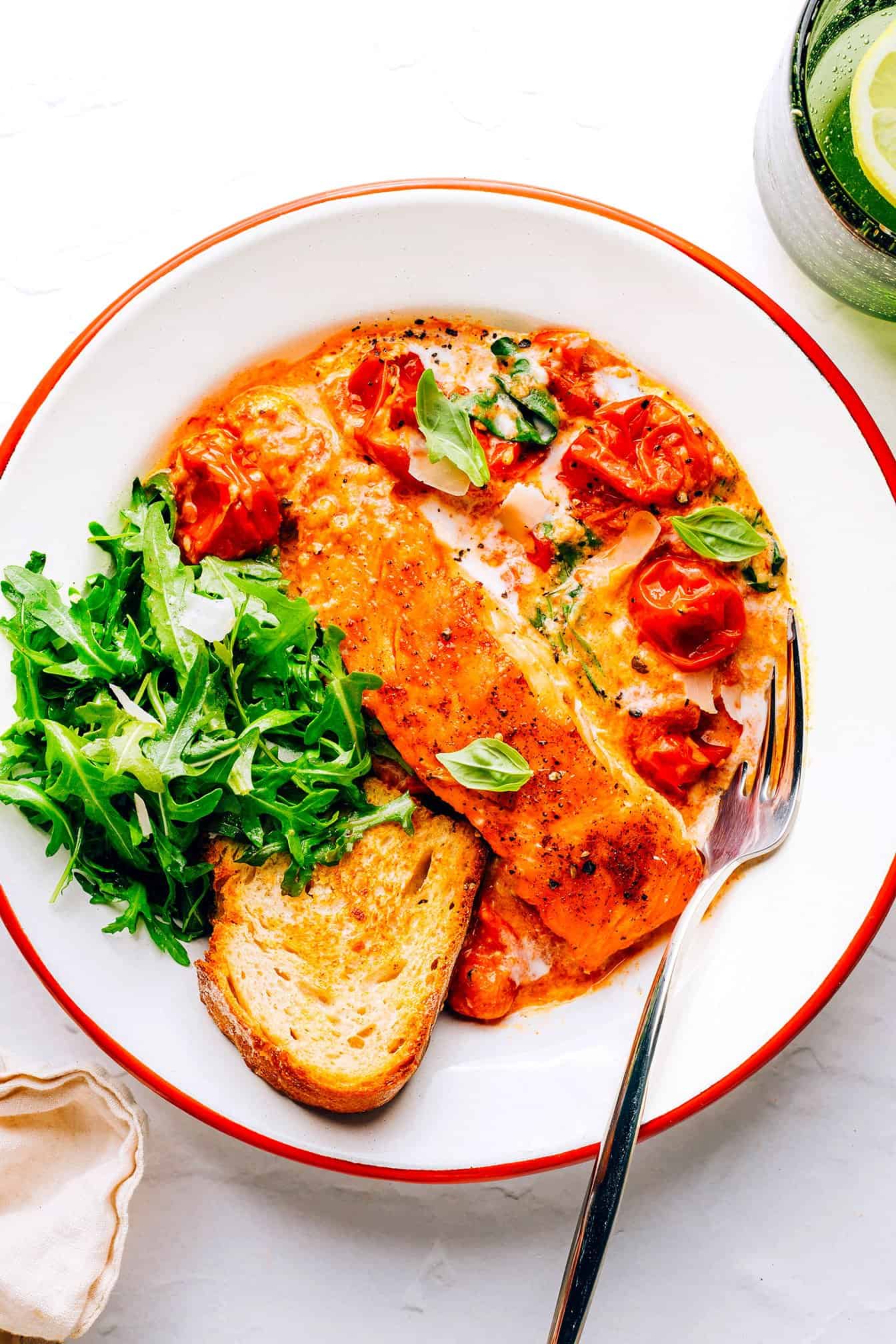 This Salmon in Burst Tomato Sauce is incredibly easy to make and simmered with the most delicious Italian-inspired garlicky cherry tomato basil cream sauce. Easy to make in 30 minutes, and delicious served for dinner with crusty bread, pasta, or rice and a simple side salad. | gimmesomeoven.com Salmon in Burst Tomato Sauce