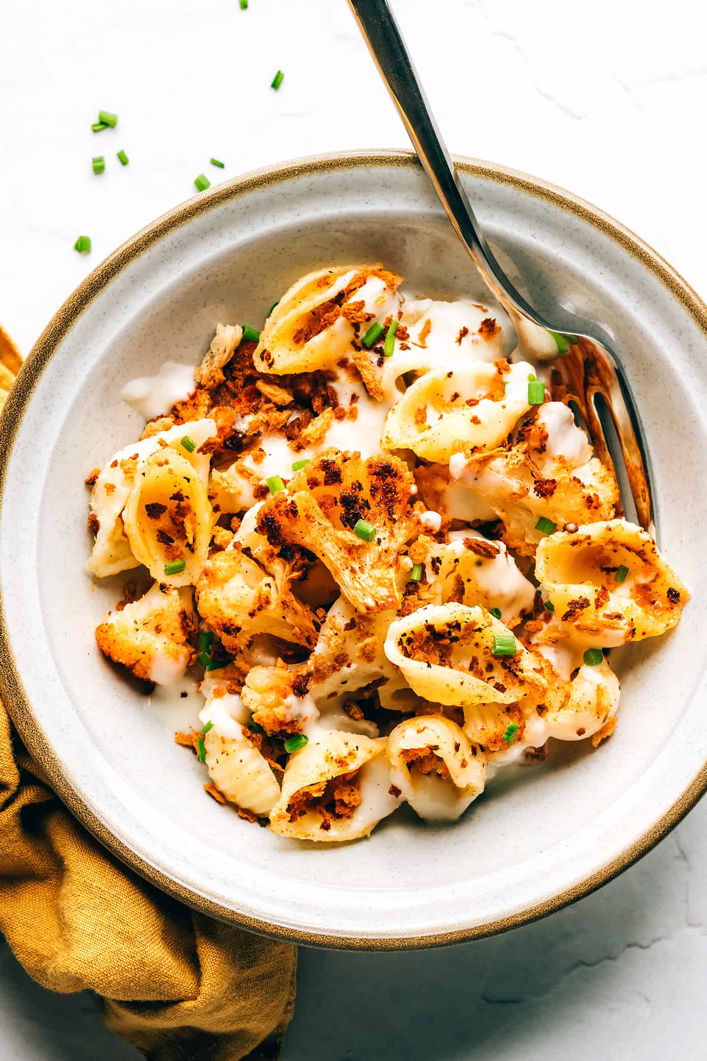 This Roasted Cauliflower Mac and Cheese features lots of zesty roasted cauliflower, a velvety cheddar cheese sauce, and sprinkling of toasted breadcrumbs. Easy to make and perfect when you're craving vegetarian comfort food for dinner. | gimmesomeoven.com Roasted cauliflower macaroni and cheese in bowl with fork