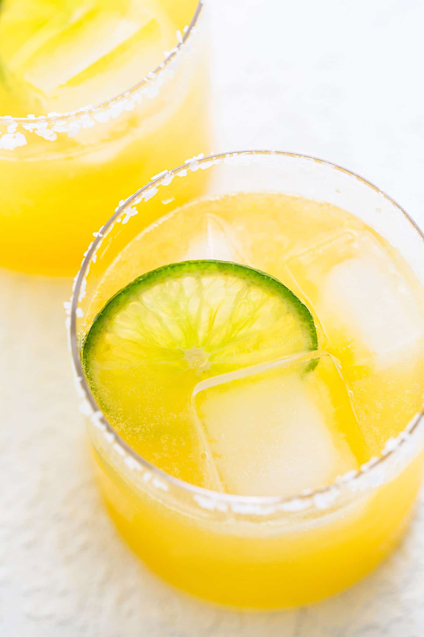 This virgin margarita mocktail recipe is quick and easy to make without alcohol, yet it's still so tangy, refreshing and delicious. Perfect to serve with your favorite Mexican food...or anytime you're craving a great mocktail! | gimmesomeoven.com Virgin Margarita Mocktail in Glasses with Lime and Salt Rims