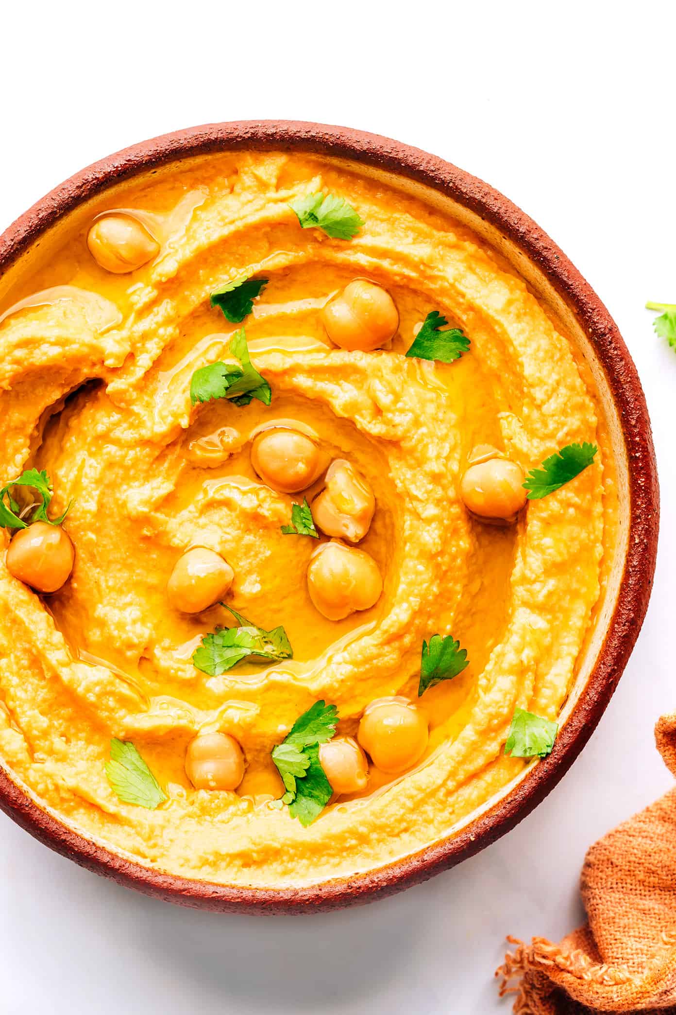 This Thai-inspired red curry hummus recipe is quick and easy to make in just 10 minutes with chickpeas, tahini, coconut milk, curry paste, ginger and garlic. Serve it up as a dip with crudités and naan, or use it as a spread on burgers or wraps. Such a great easy appetizer! | gimmesomeoven.com Thai Red Curry Hummus in Bowl with Chickpeas