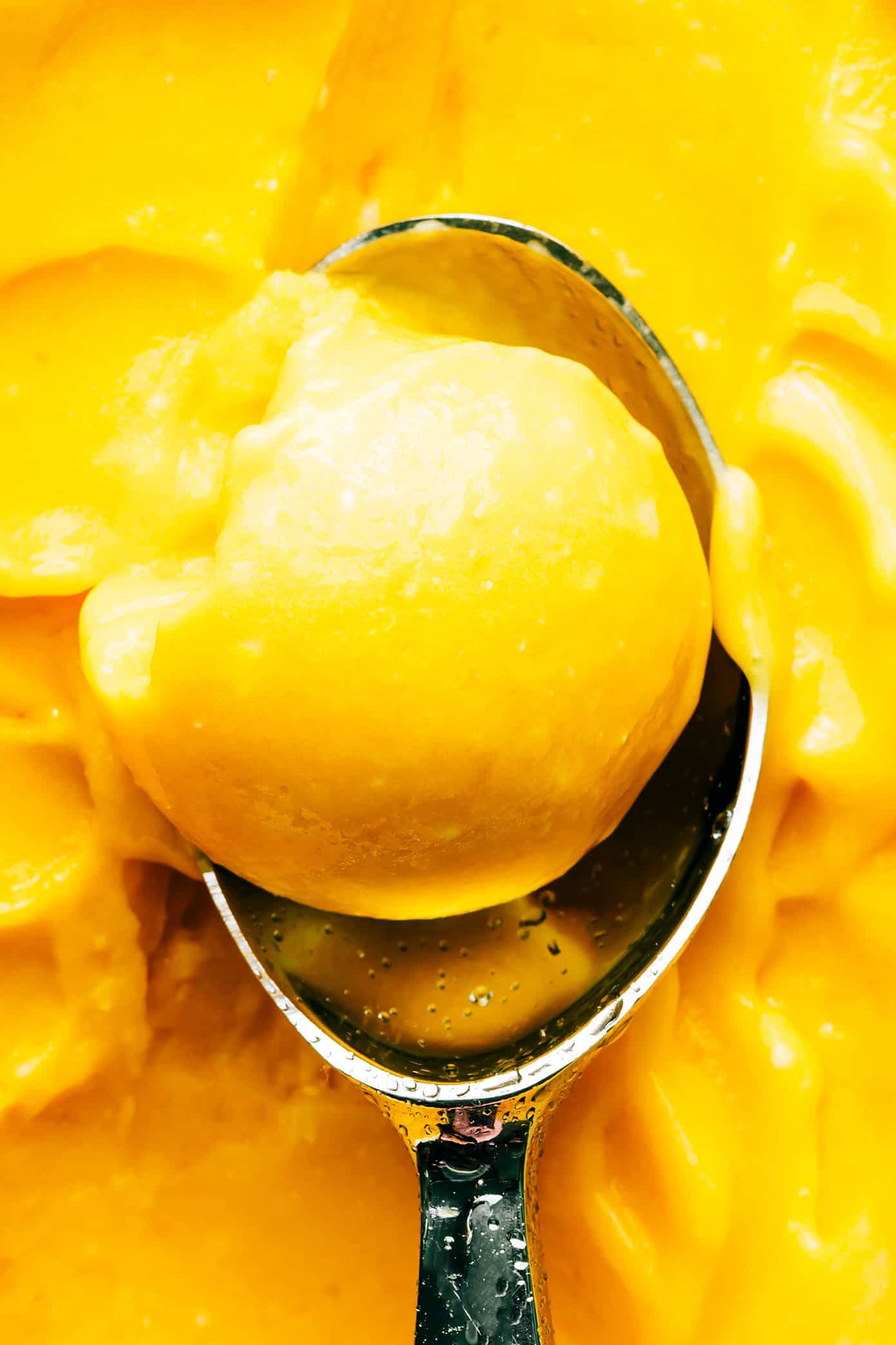 This 5-minute mango lime sorbet is easy to make in a food processor or blender, and made with a delicious blend of mango, lime, coconut milk and fresh ginger. It's the perfect refreshing dessert for summer entertaining, and naturally gluten-free, dairy-free, vegetarian and vegan. | gimmesomeoven.com Mango Lime Sorbet Scoop Closeup
