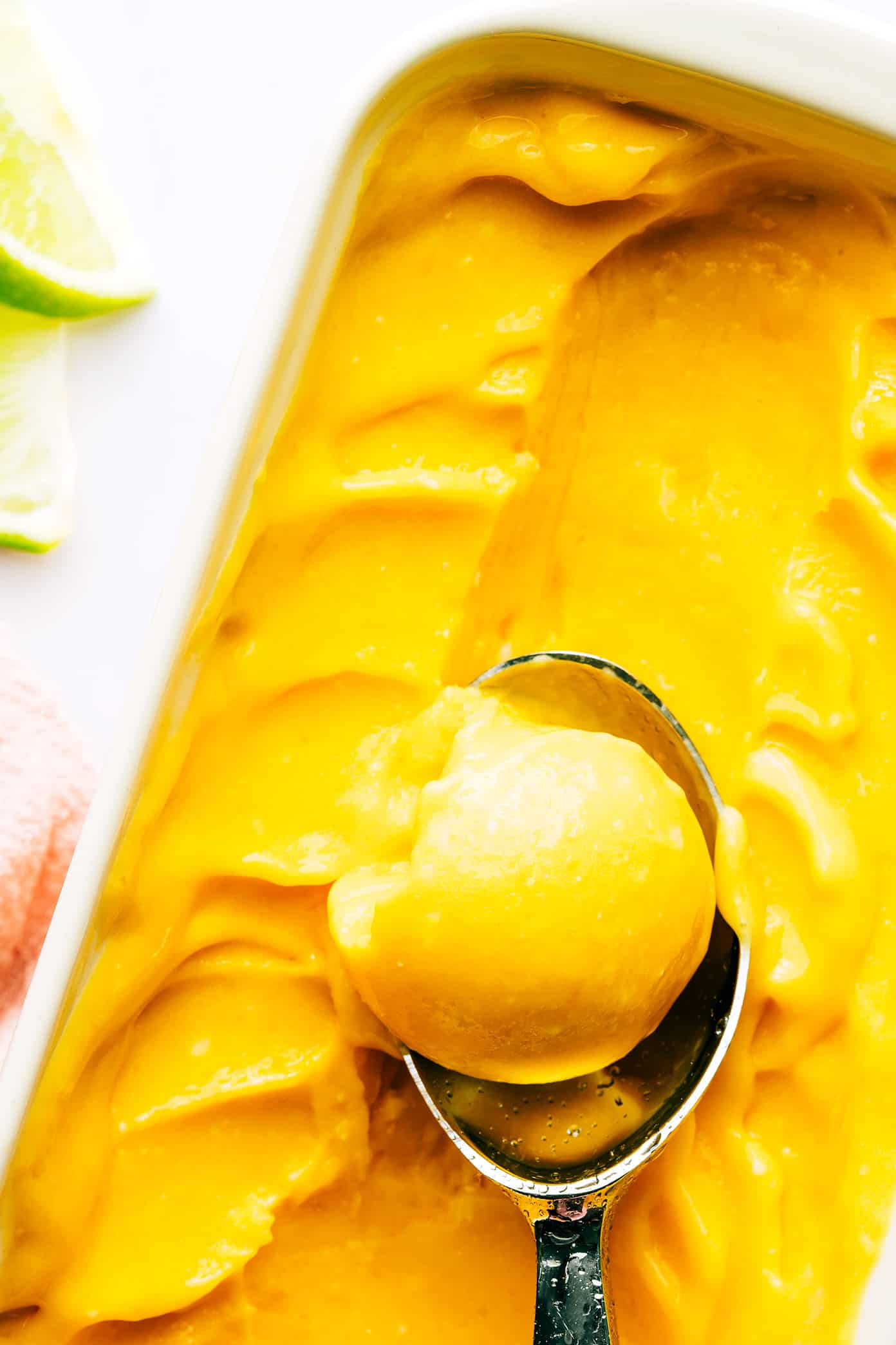 This 5-minute mango lime sorbet is easy to make in a food processor or blender, and made with a delicious blend of mango, lime, coconut milk and fresh ginger. It's the perfect refreshing dessert for summer entertaining, and naturally gluten-free, dairy-free, vegetarian and vegan. | gimmesomeoven.com Mango Lime Sorbet in Pan with Ice Cream Scoop